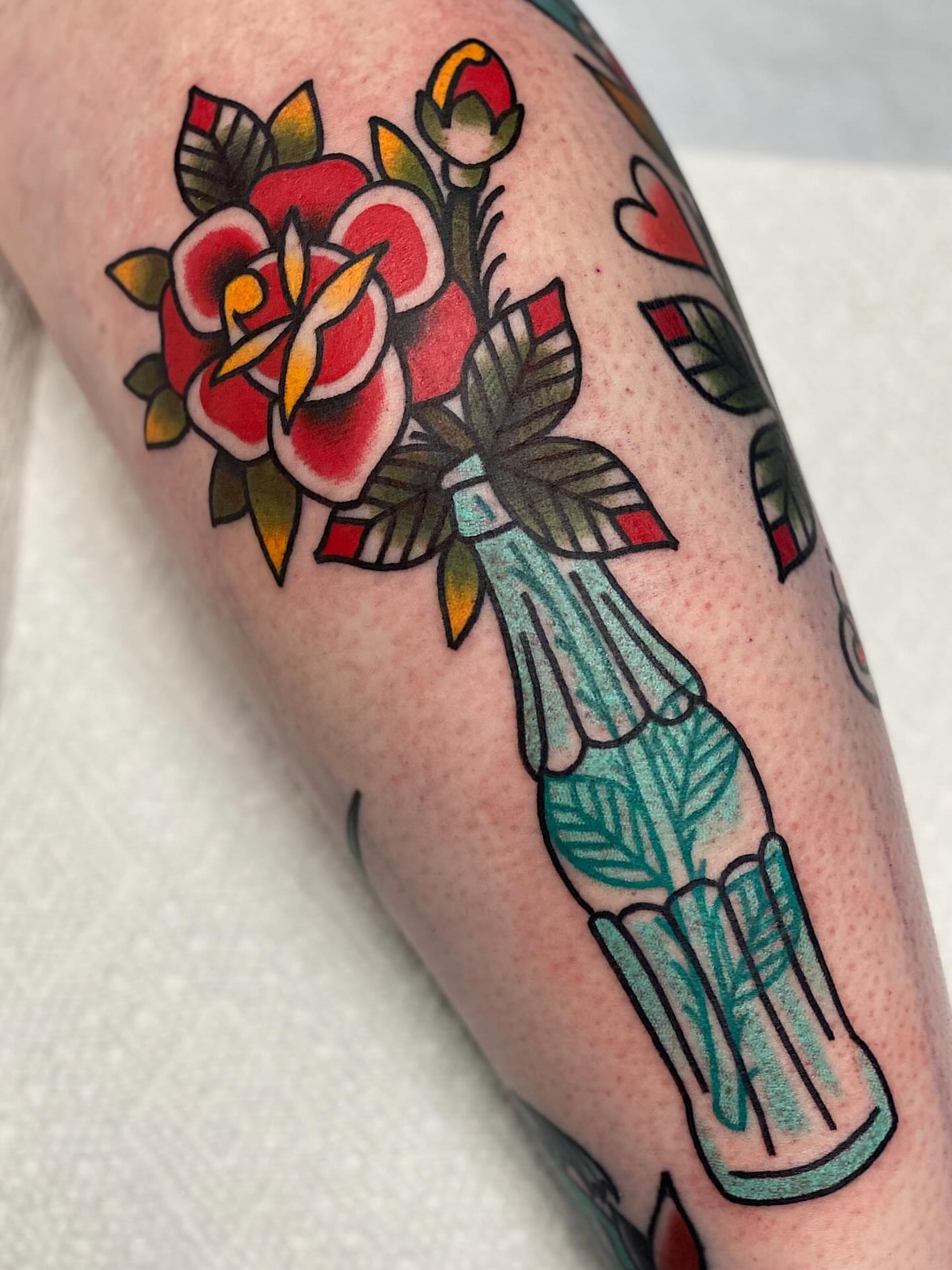 Flower and bottle American traditional tattoo on the forearm by Dakota Amato