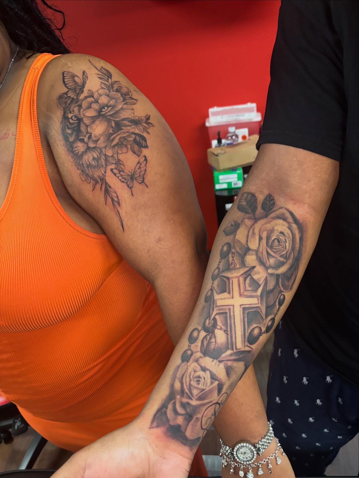 Roses and cross realism tattoo on the upper arm by Dre Ortiz