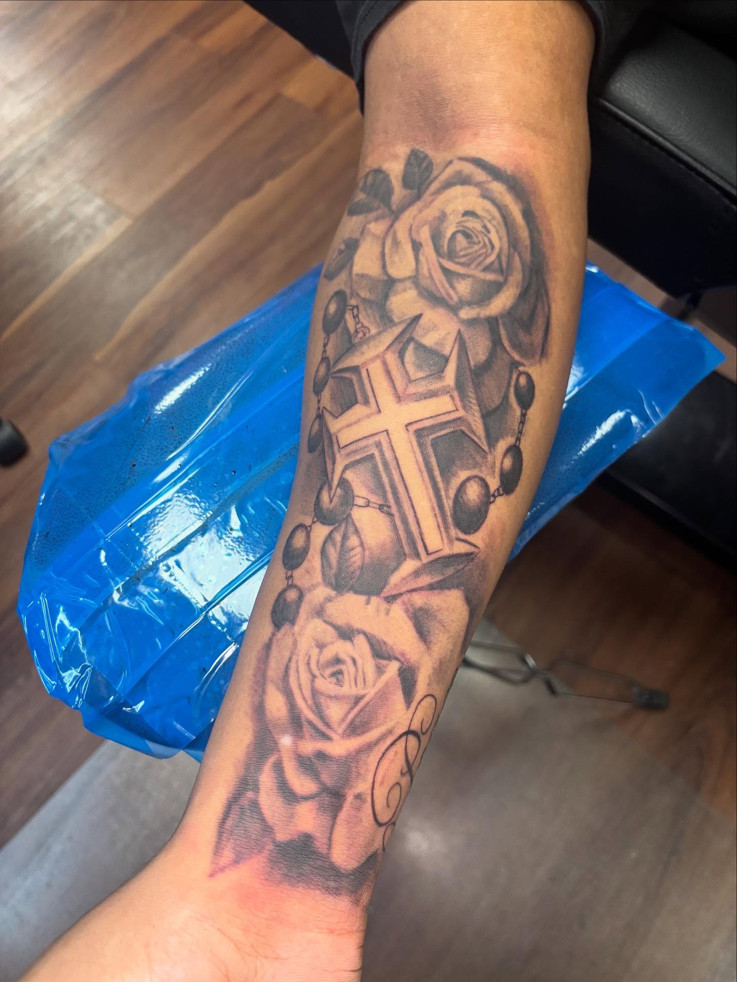 Roses and cross realism tattoo on the forearm by Dre Ortiz