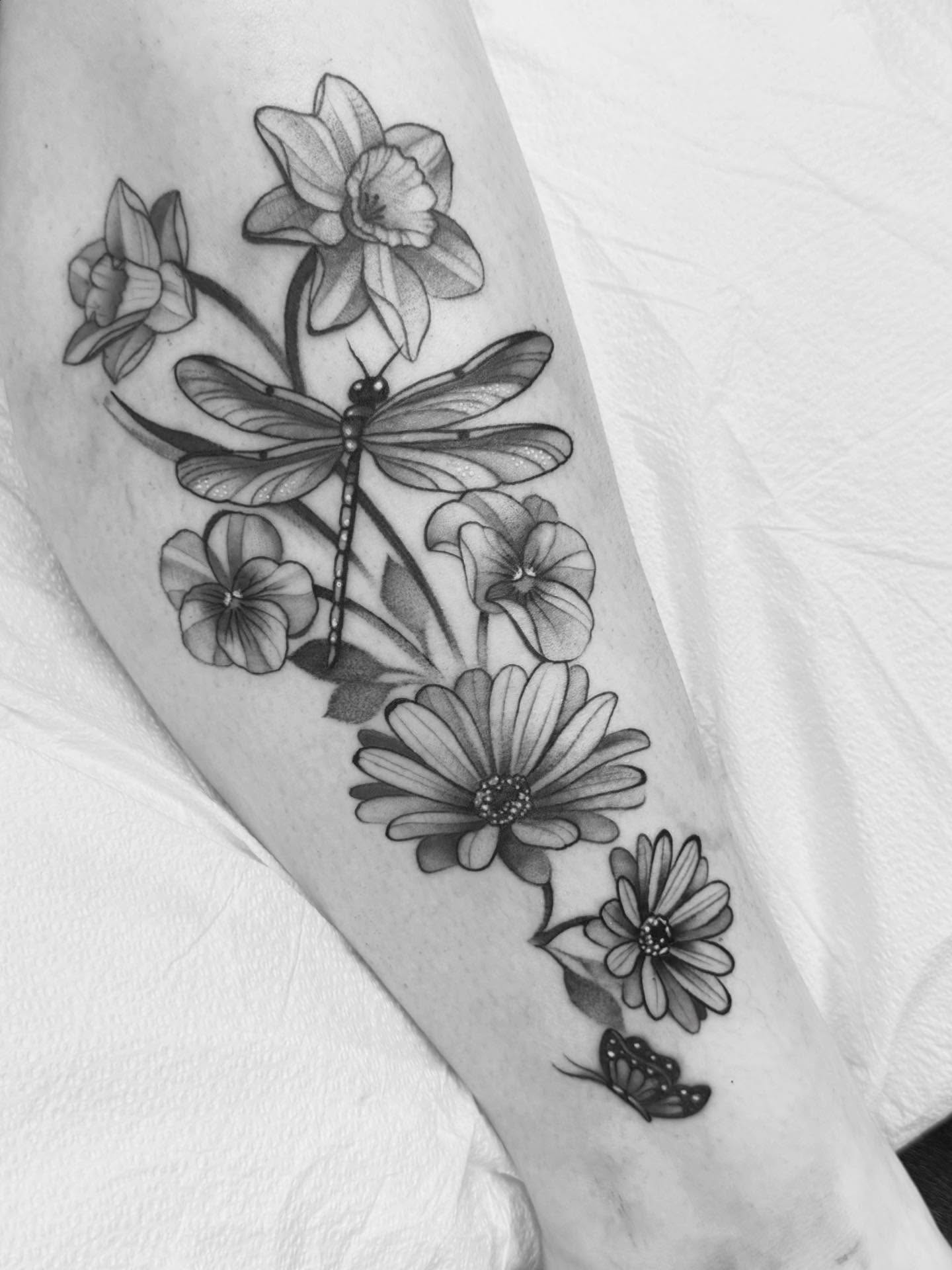 Flowers and dragonfly black and grey tattoo on the forearm by Connie Fiorino - Tattoo Artist