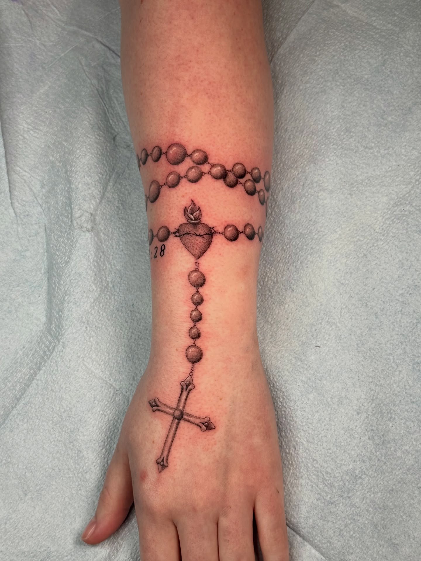 Rosary black and grey tattoo on the forearm by Truett Payton