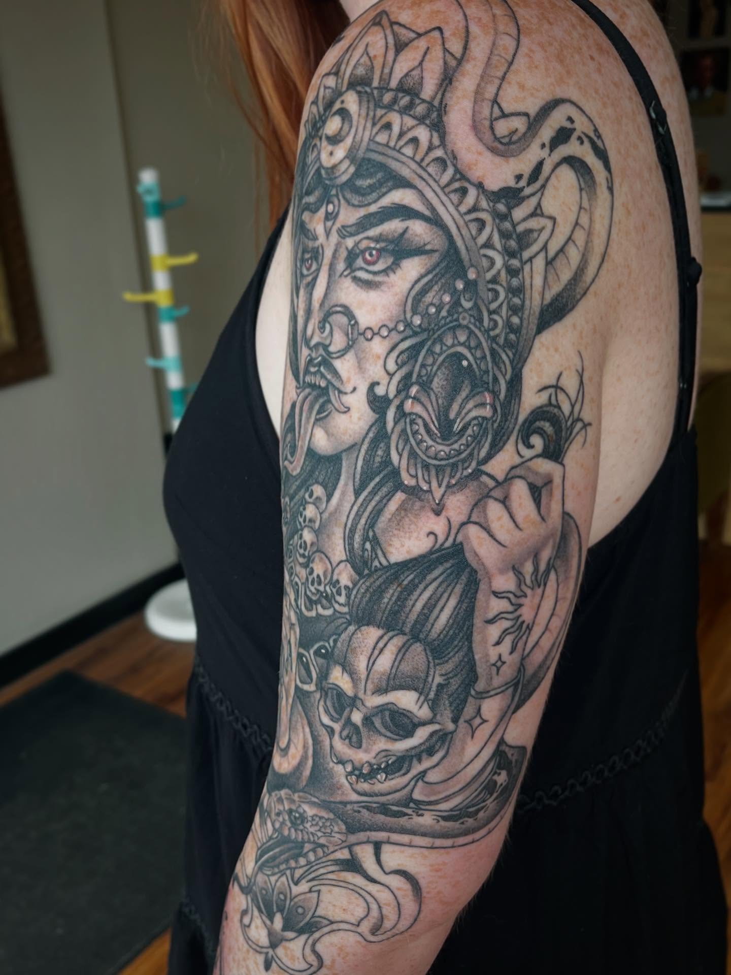 Woman with skull realism tattoo on the upper arm by Taylor Santavicca
