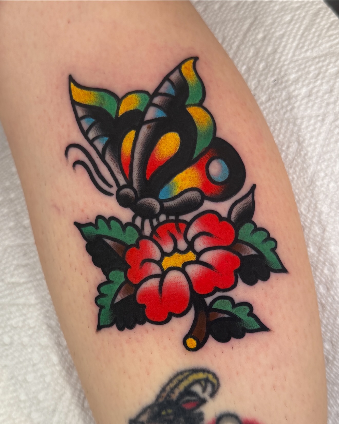 Butterfly and flower American traditional tattoo on the forearm by Cullen Bleser Quinn