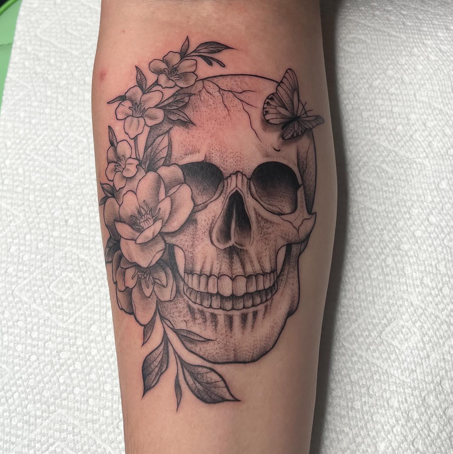 Skull with flowers dotwork tattoo on the forearm by Lexi Ross