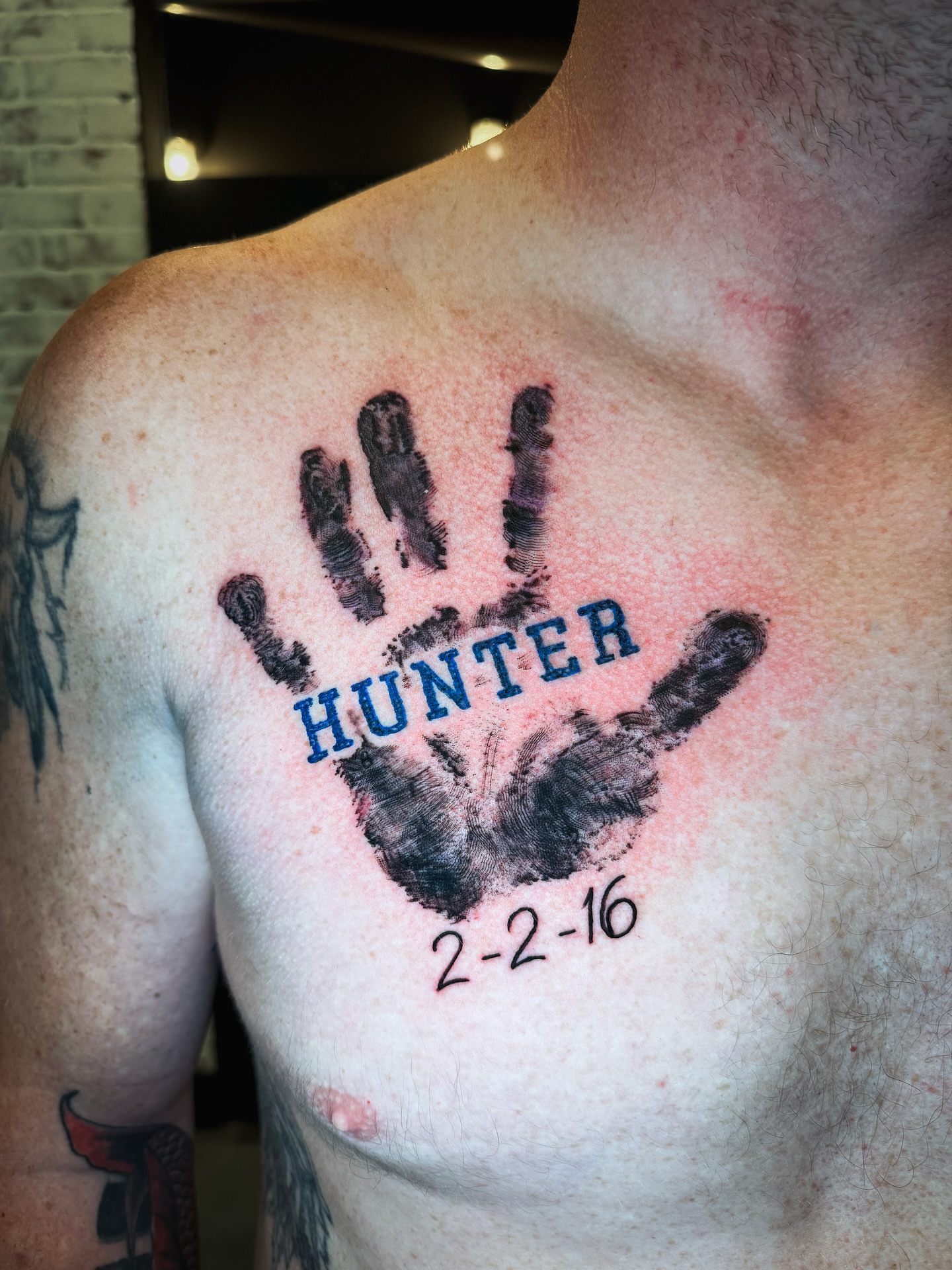 Handprint with name and date dotwork tattoo on the chest by Brandt Norcross