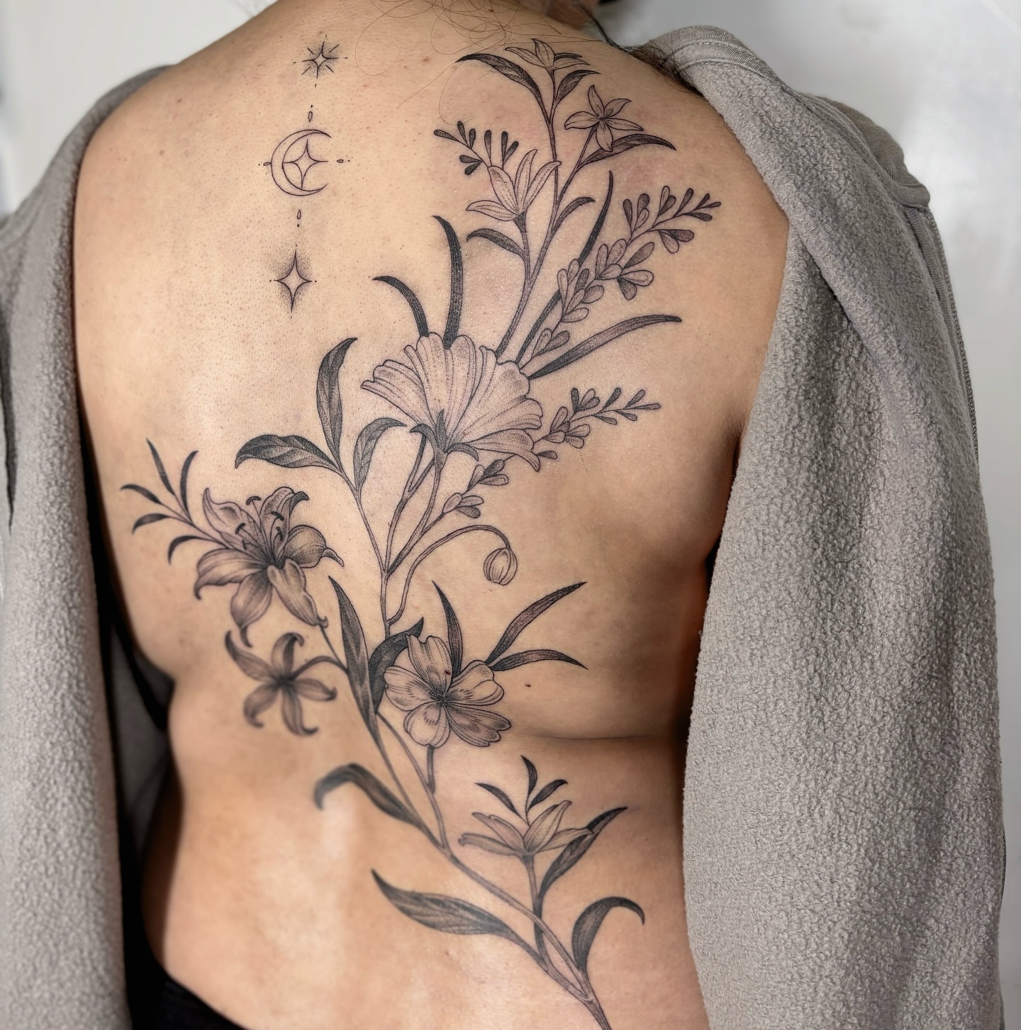 Floral bouquet realism tattoo on the back by Kinsey Miller