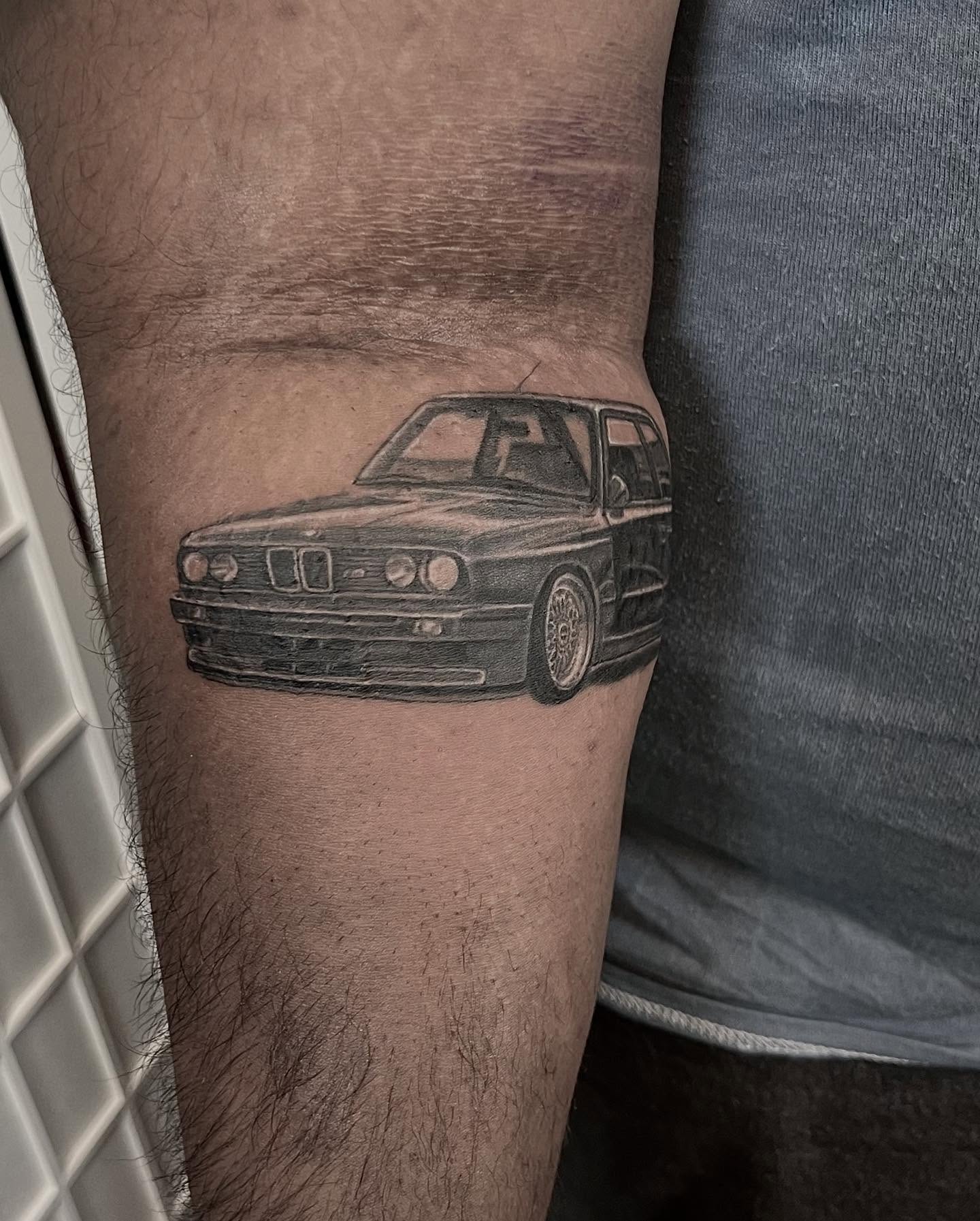 Bmw station wagon black and grey tattoo on the forearm by Tattoo Artist