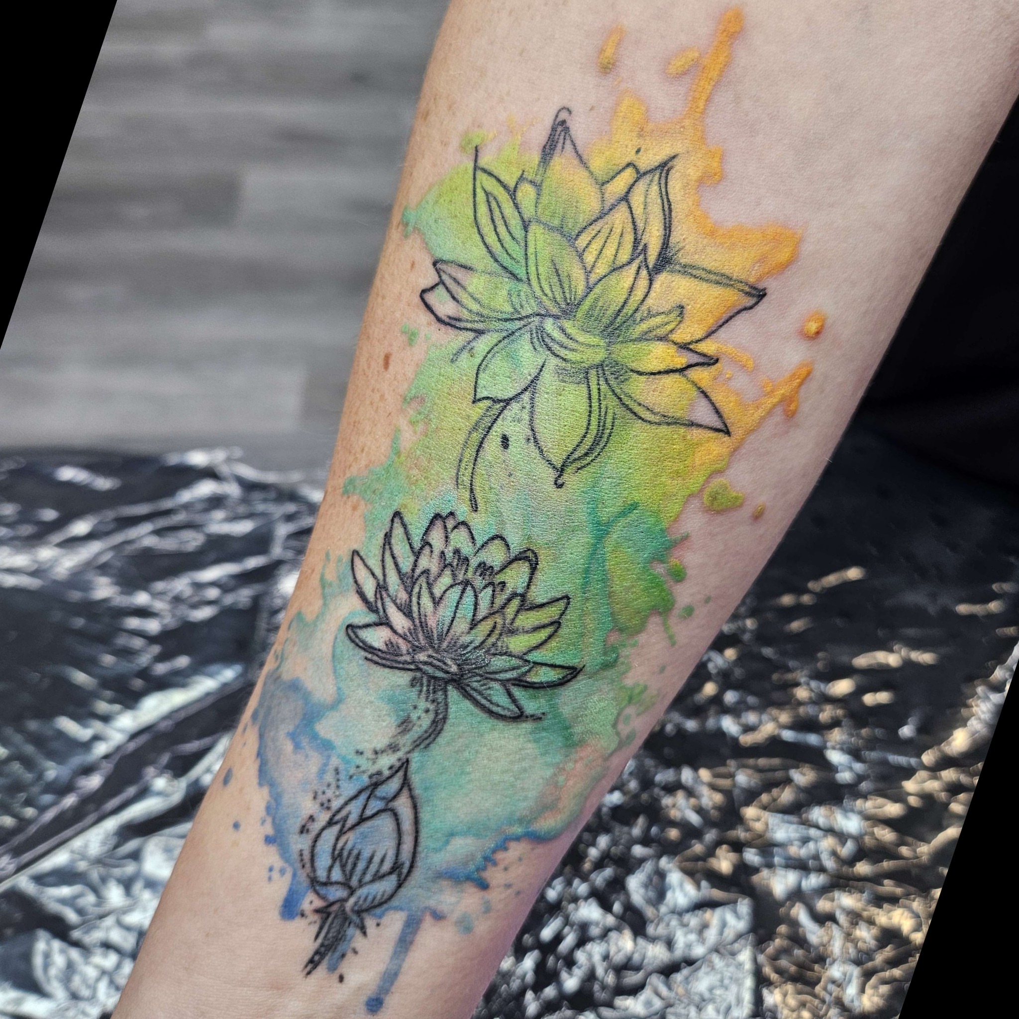 Lotus flowers watercolor tattoo on the forearm by Iram Withencroft