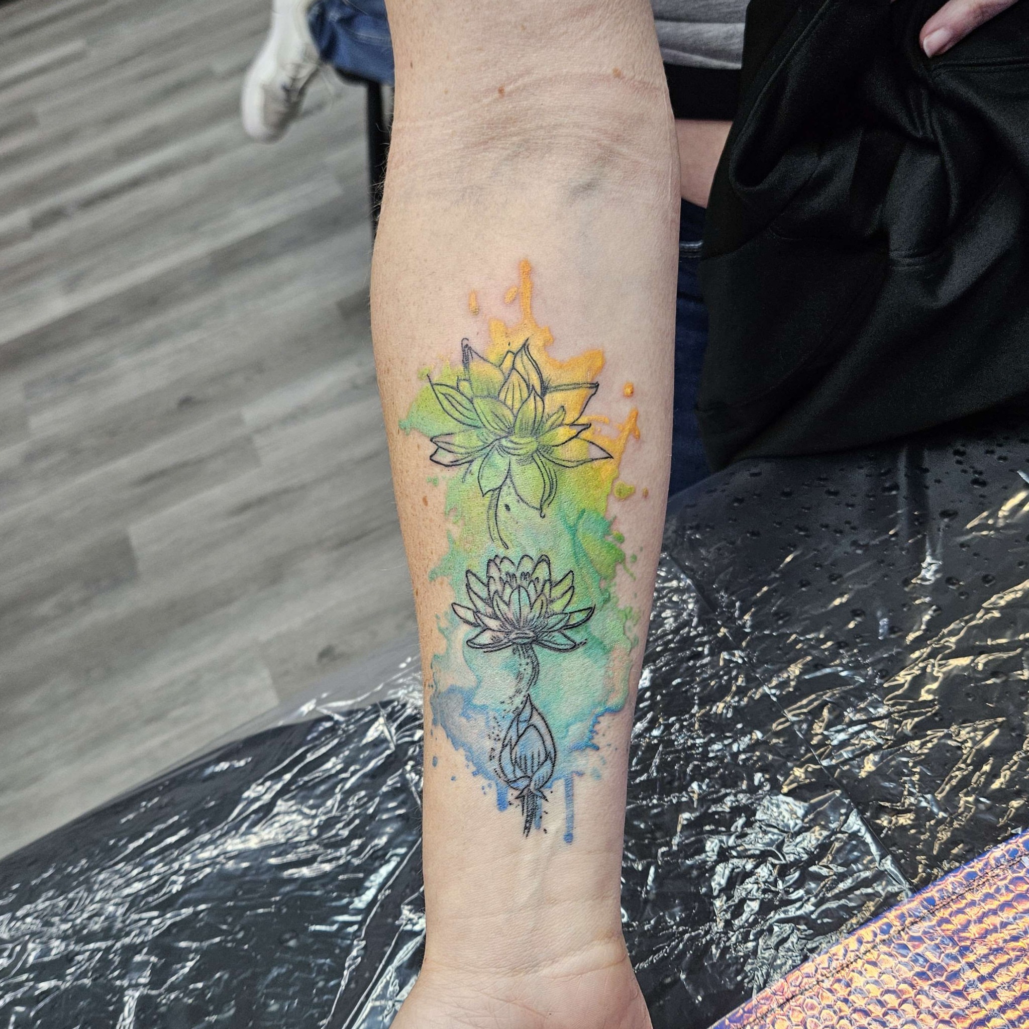 Lotus flower watercolor tattoo on the forearm by Iram Withencroft