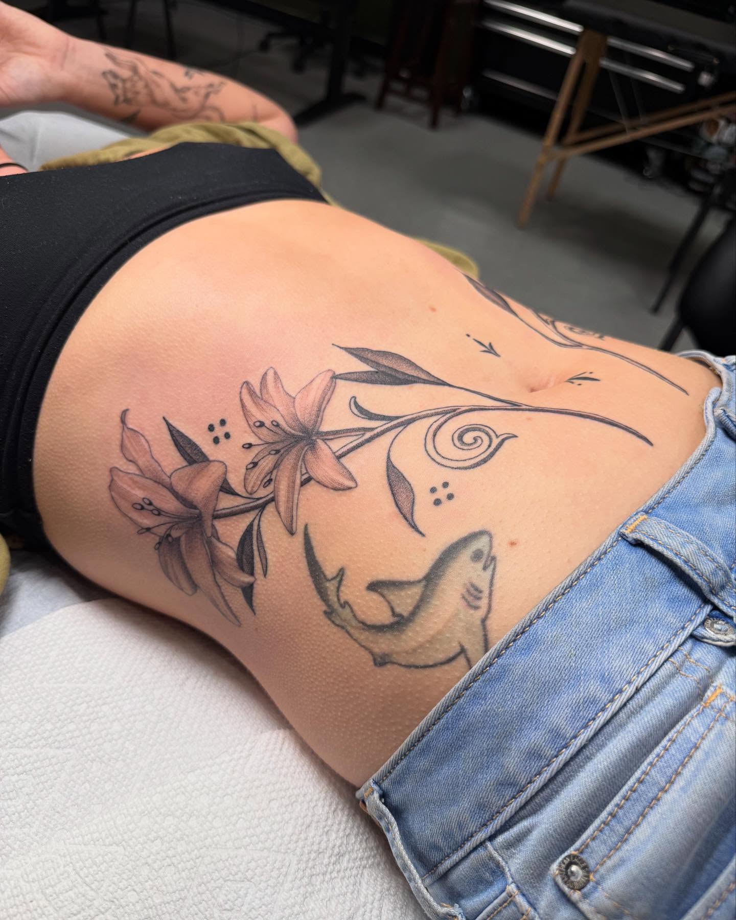 Lilies and shark black and grey tattoo on the ribs by Maddie Jo DeYoung