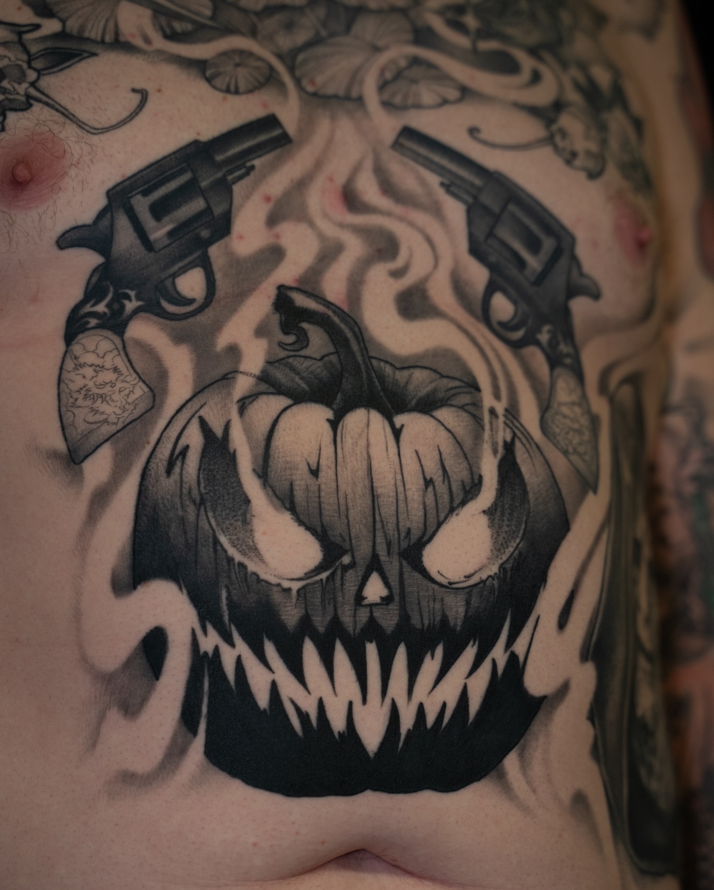 Pumpkin with guns dark realism tattoo on the chest by Chris Estrada