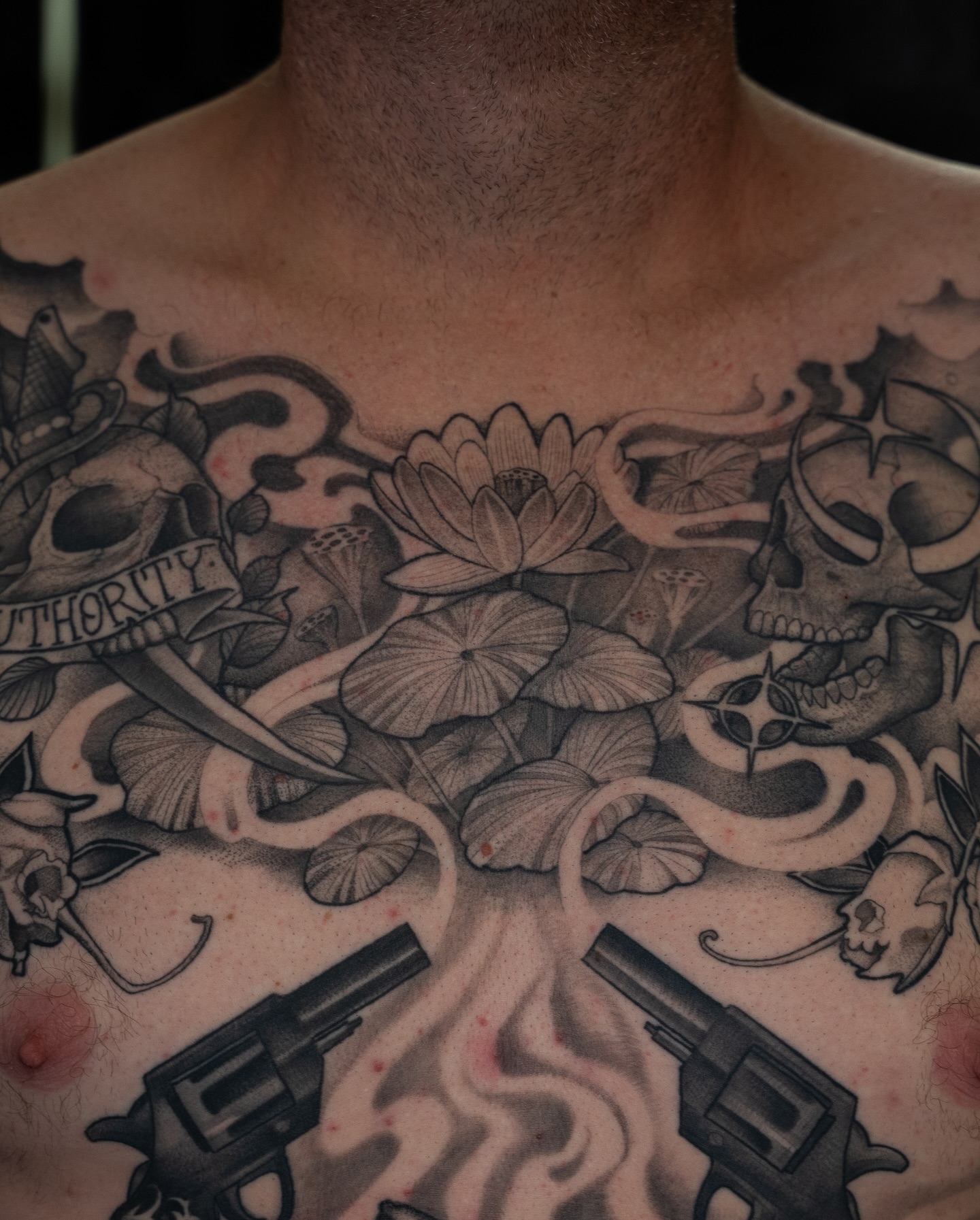 Lotus flowers and skulls neo-traditional tattoo on the chest by Chris Estrada