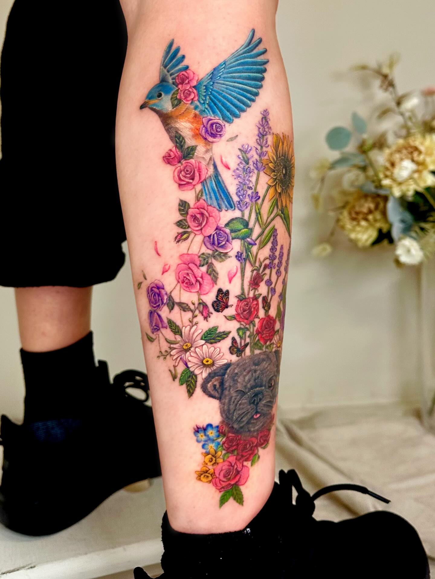 Bird and floral bouquet realism tattoo on the calf by Claire