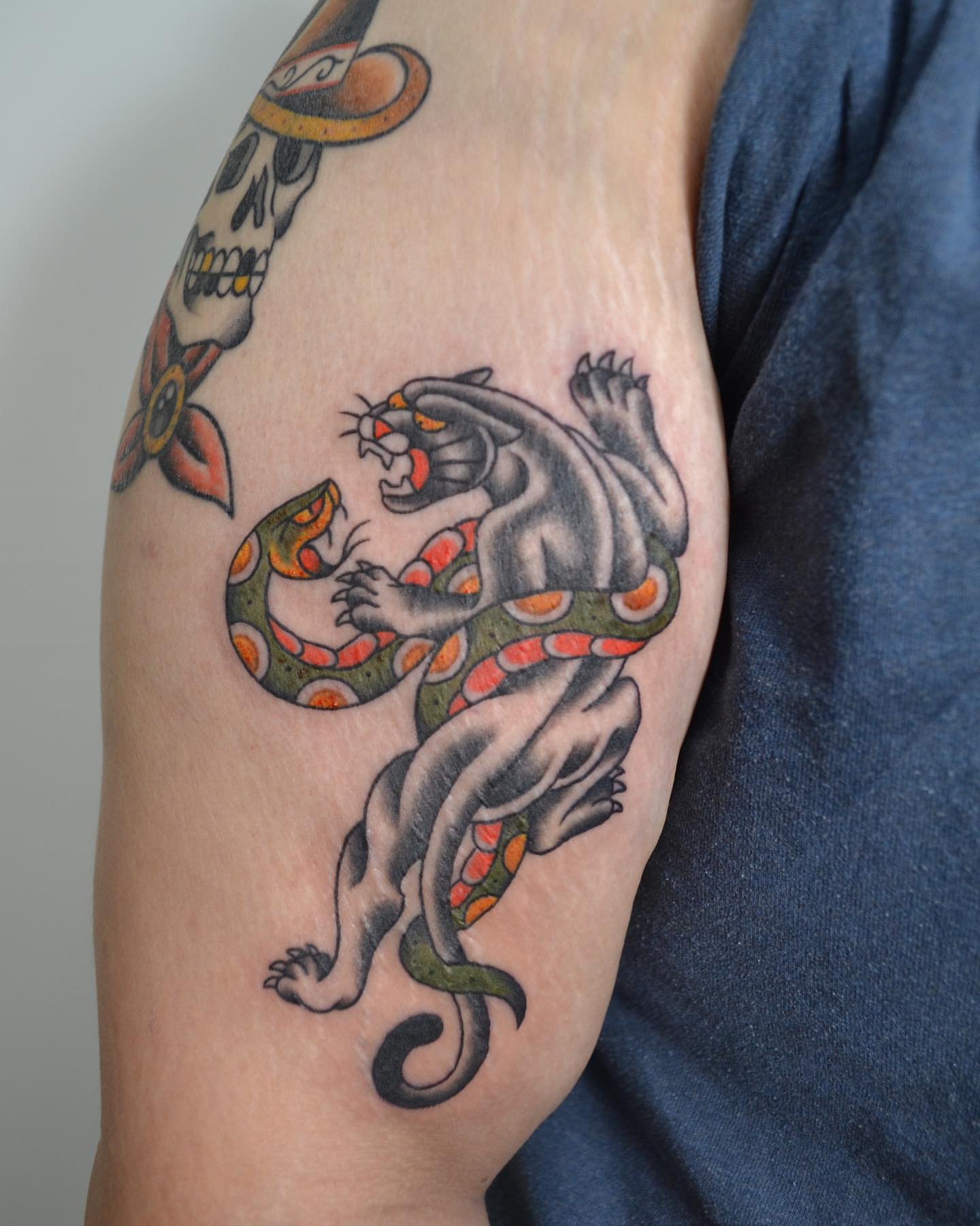 Panther and snake American traditional tattoo on the upper arm by Vanessa Acosta