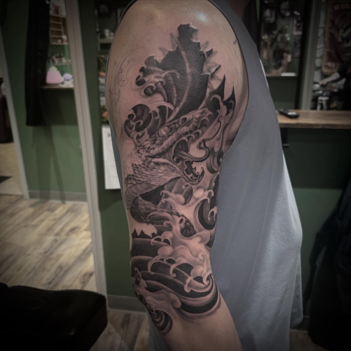 Dragon realism tattoo on the upper arm by Blake Van Vleck
