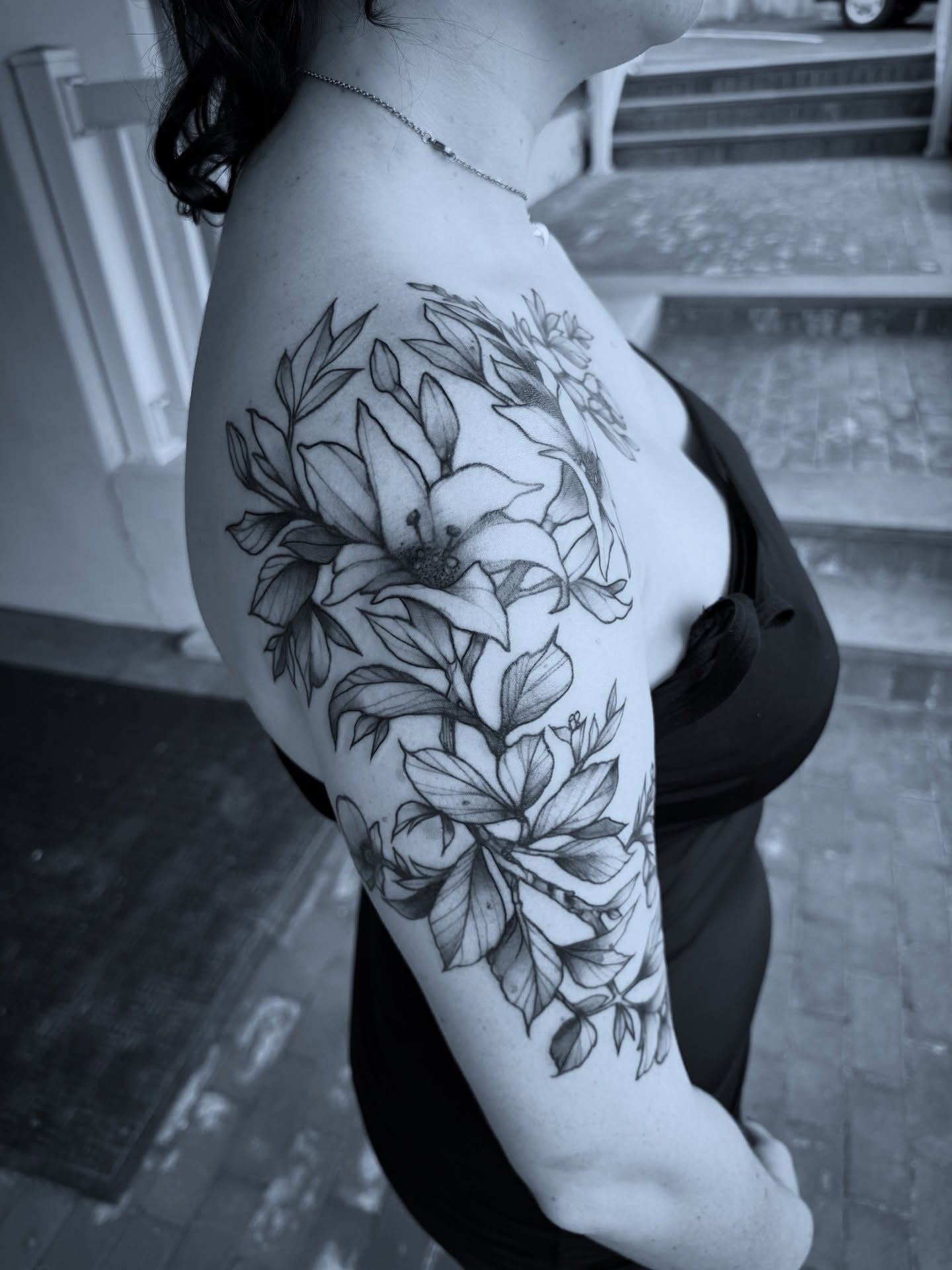 Flowers black and grey tattoo on the upper arm by Michael Langdale