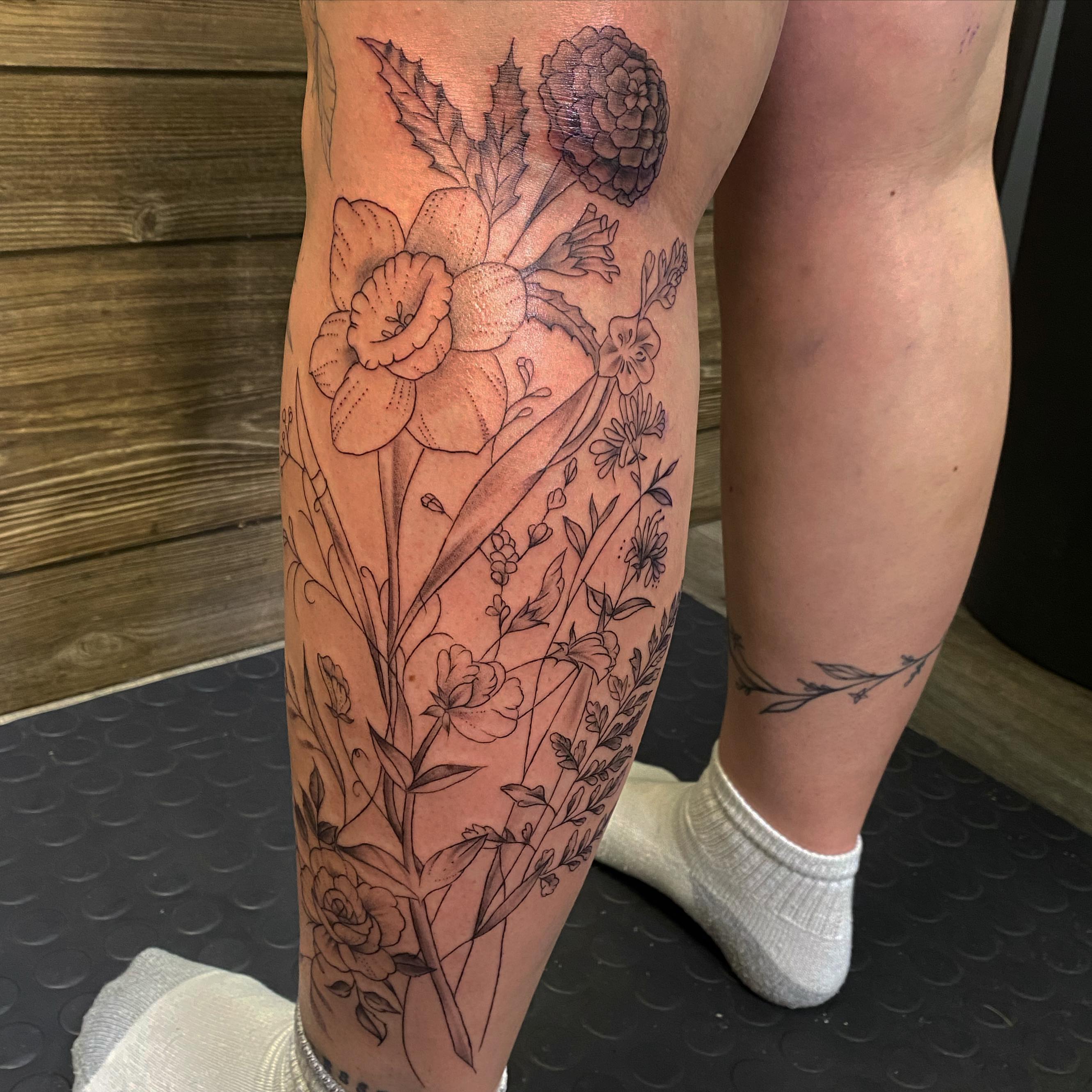 Floral bouquet realism tattoo on the calf by Spencer Jones Tattoos
