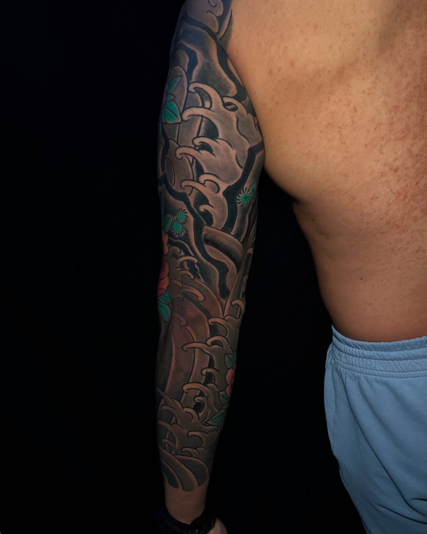 Waves and flowers japanese irezumi tattoo on the upper arm by Andrew Snowden