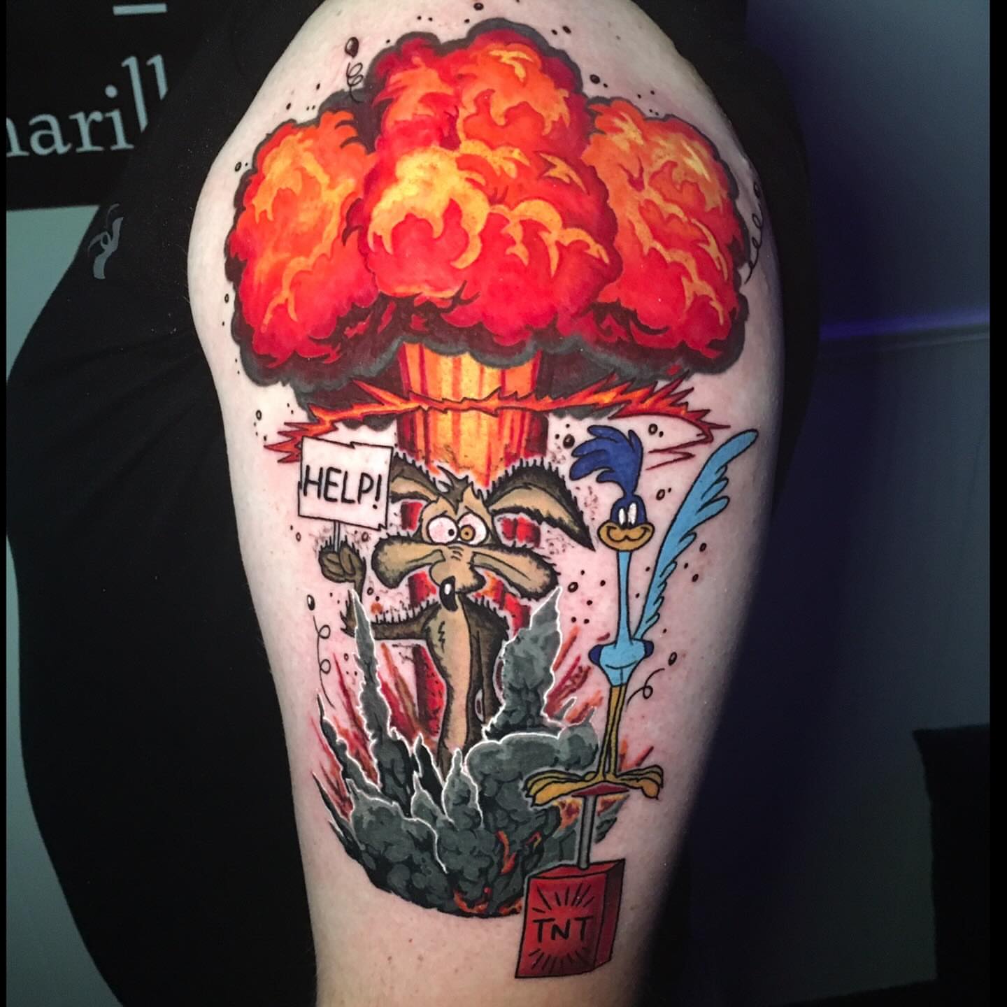 Bomb explosion trash polka tattoo on the upper arm by Joshua Shawn