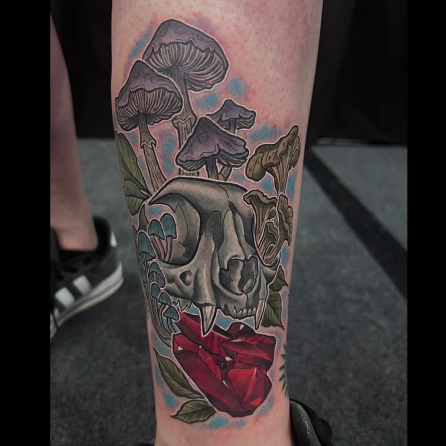 Skull with mushrooms and rose realism tattoo on the forearm by Joshua Shawn