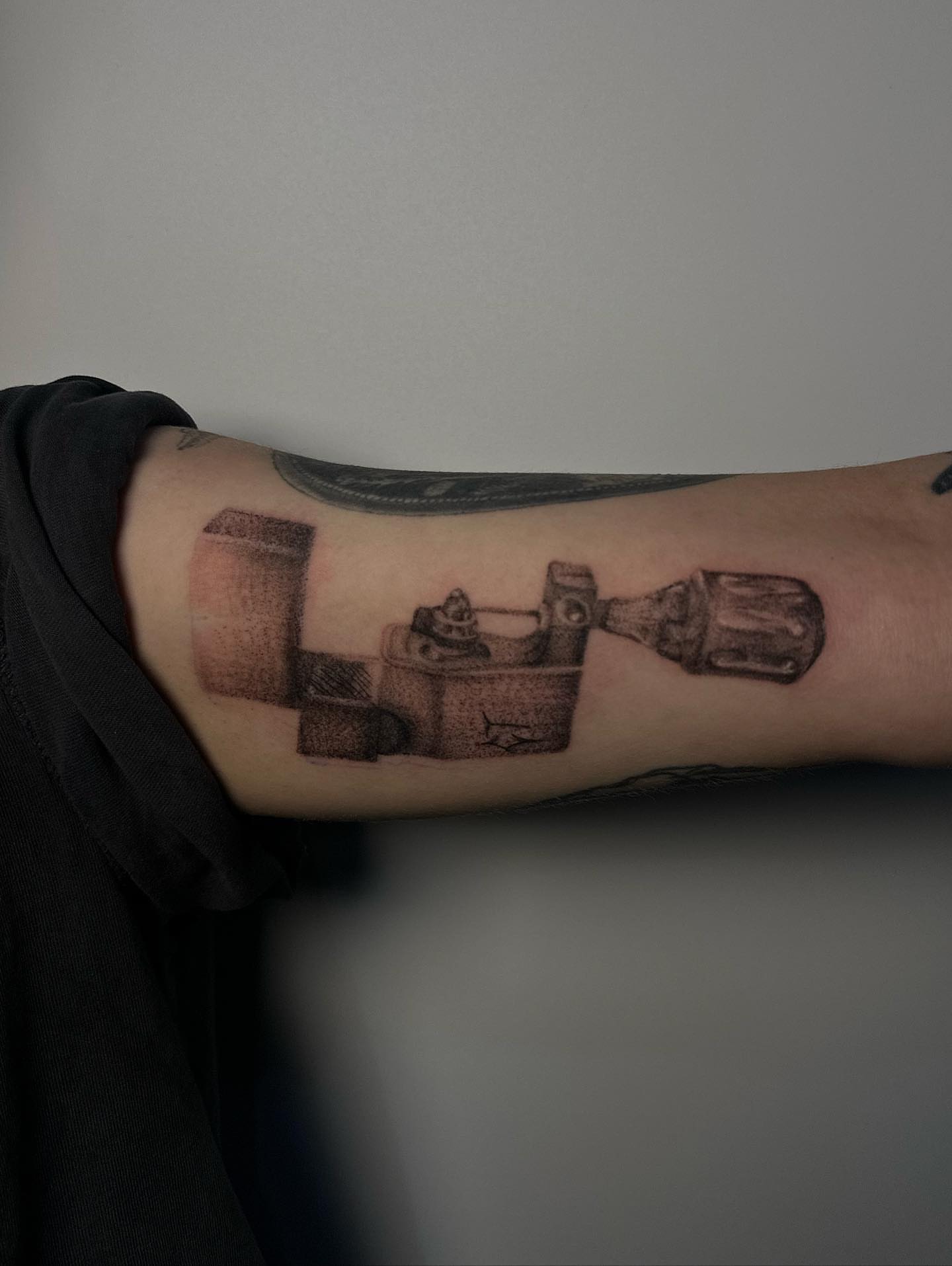 Sewing machine black and grey tattoo on the forearm by Lee