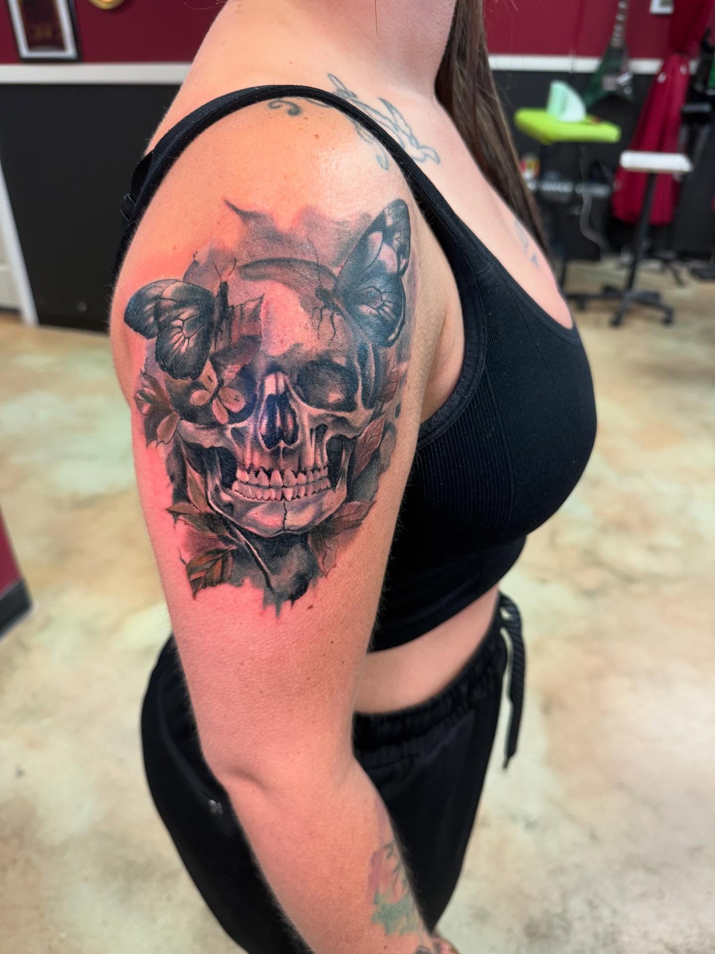 Skull with flowers realism tattoo on the shoulder by Shawn Cook