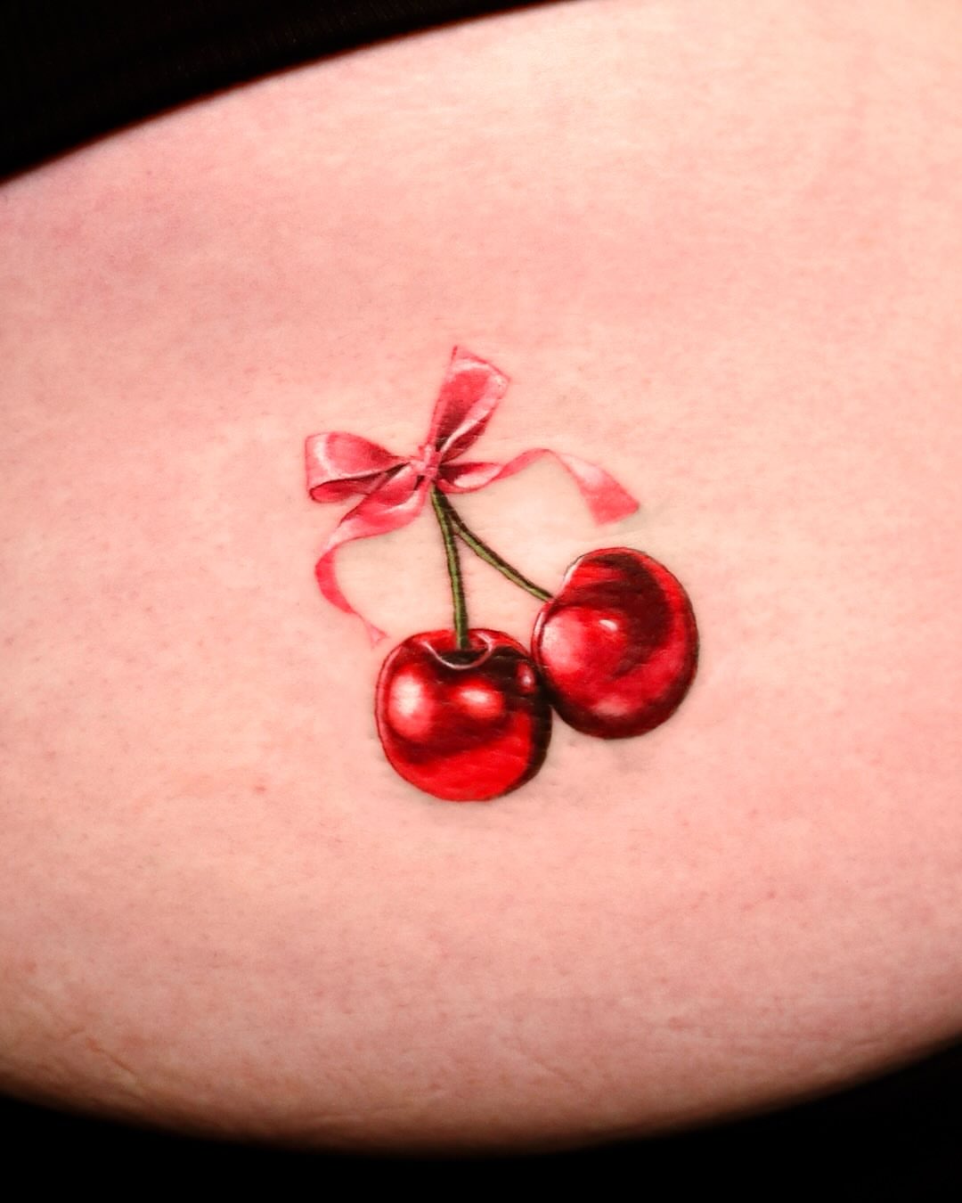 Cherries with ribbon realism tattoo on the forearm by Mei
