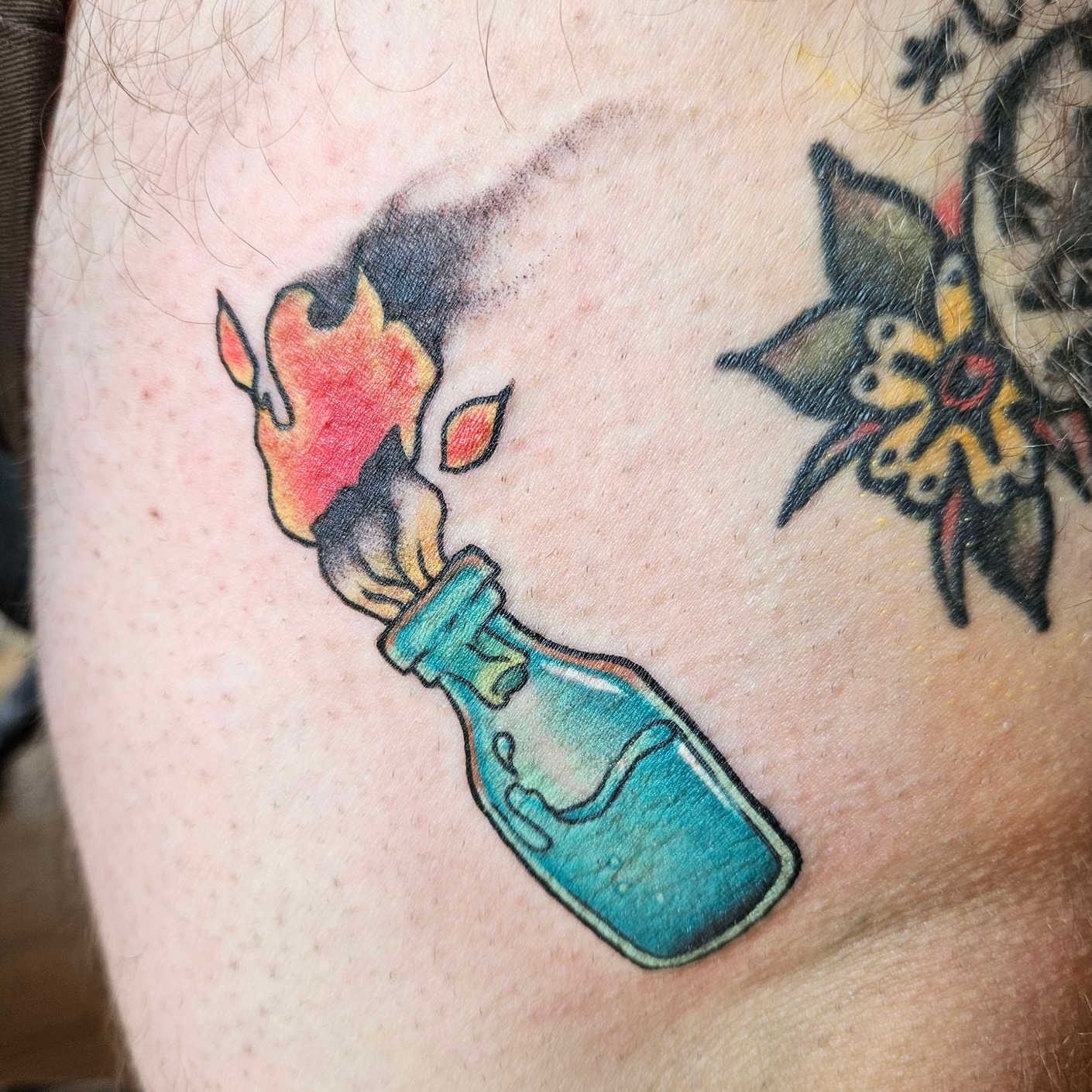 Flame in bottle American traditional tattoo on the thigh by Iram Withencroft