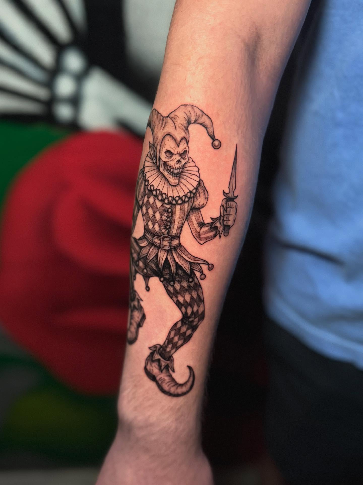Jester black and grey tattoo on the forearm by Koko