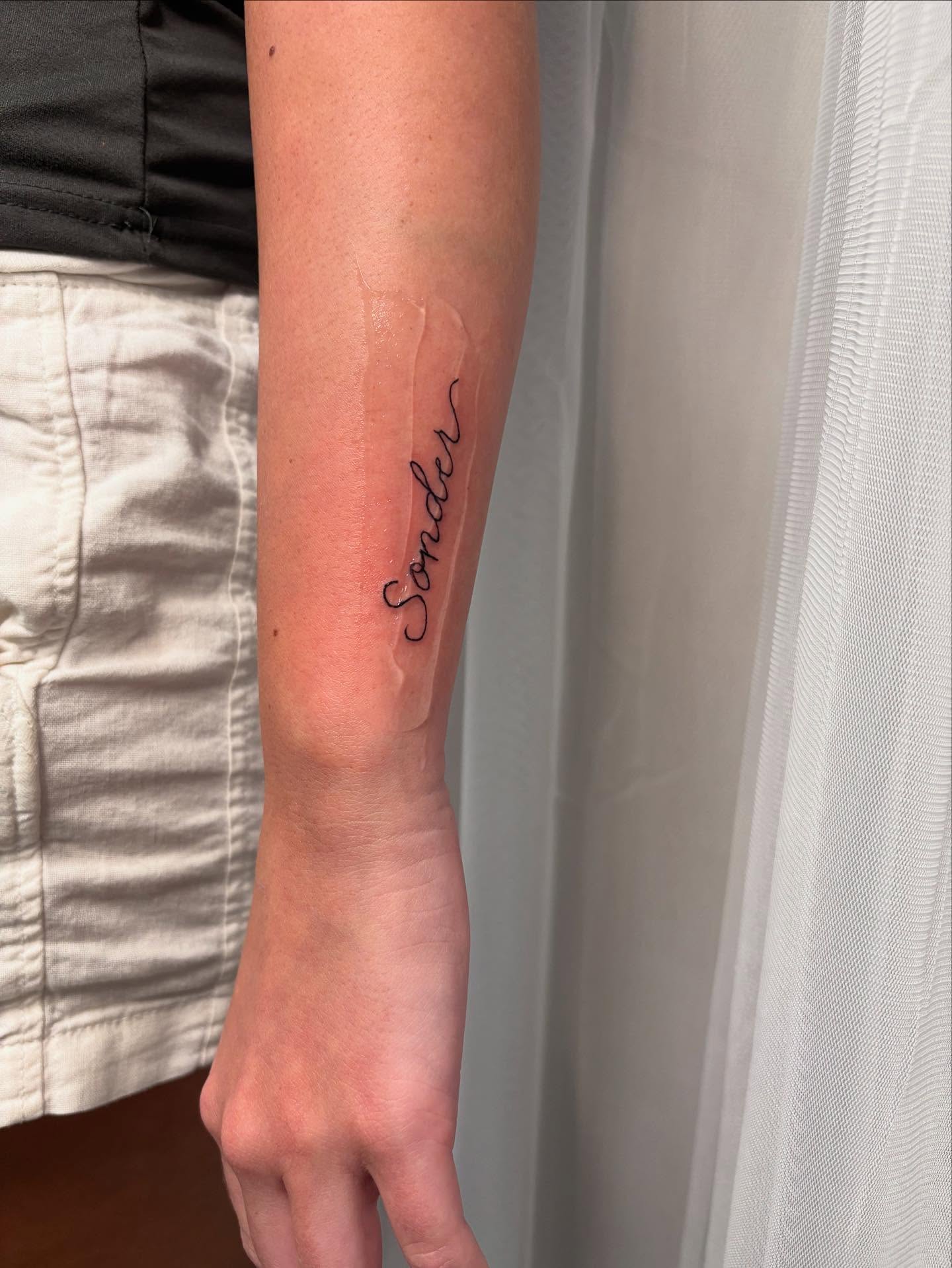 Sonder lettering script tattoo on the forearm by Victoria Cooper