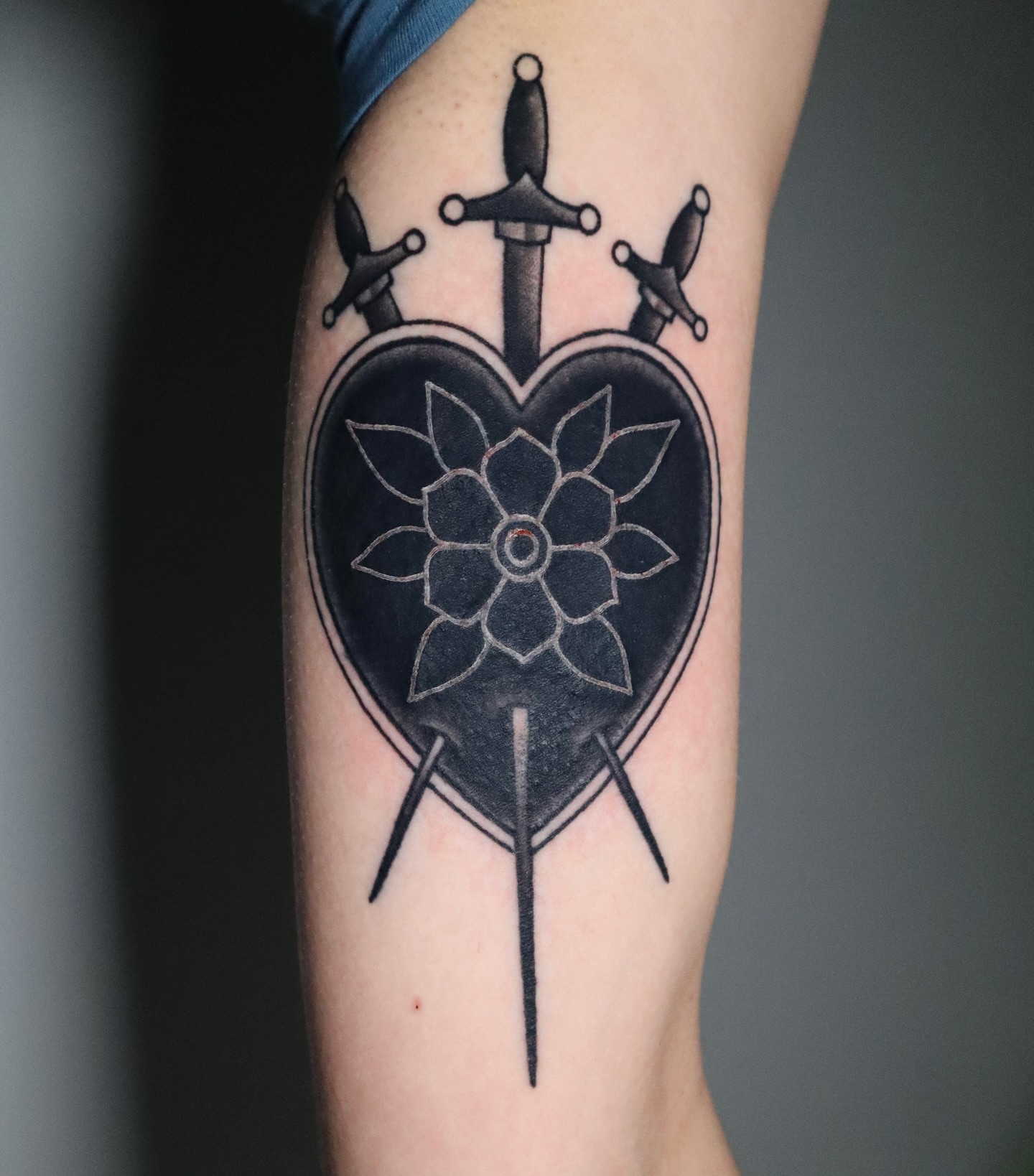 Heart with flower and swords black and grey tattoo on the forearm by Lauren Howard Tattoos