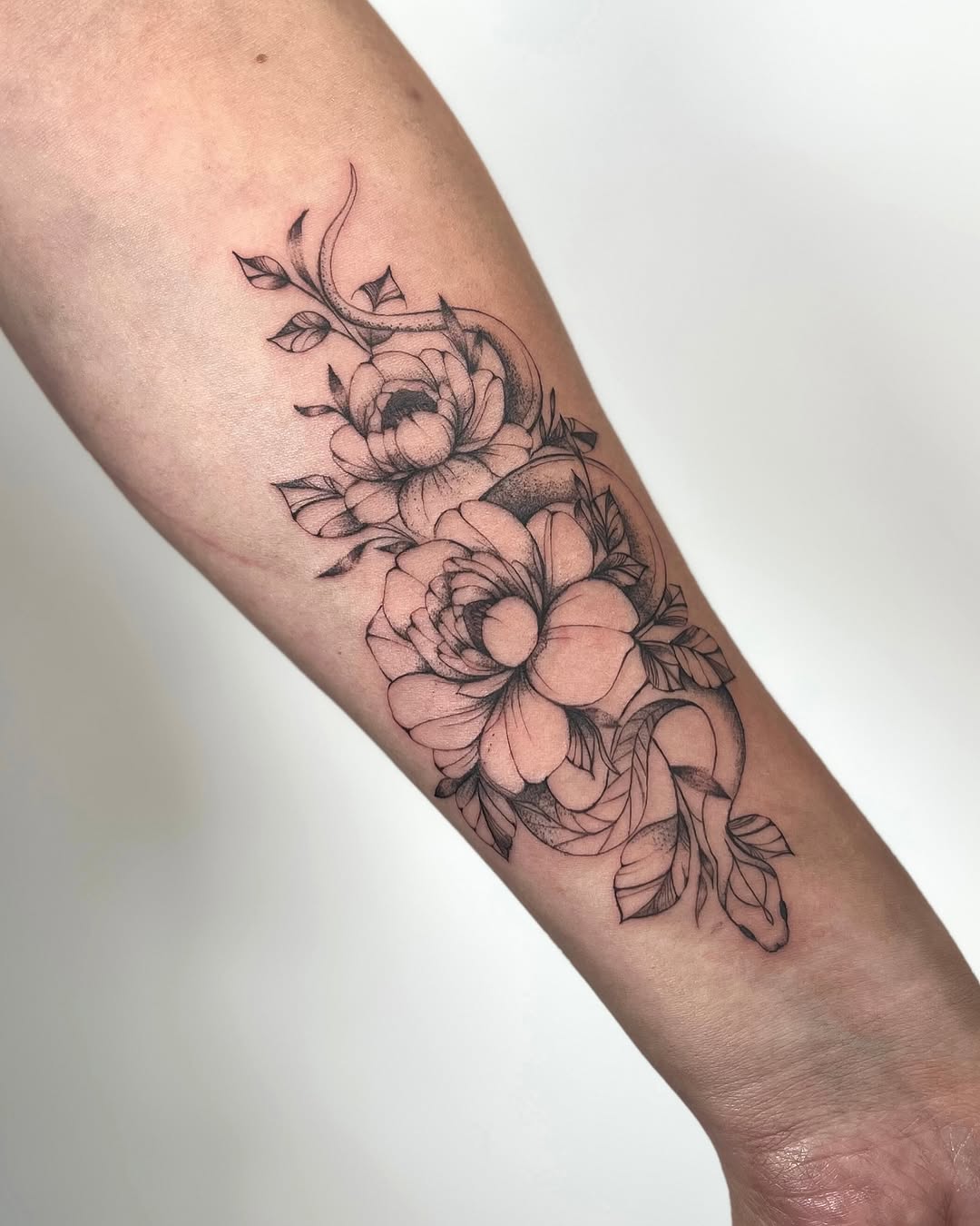 Snake and peonies dotwork tattoo on the forearm by kt