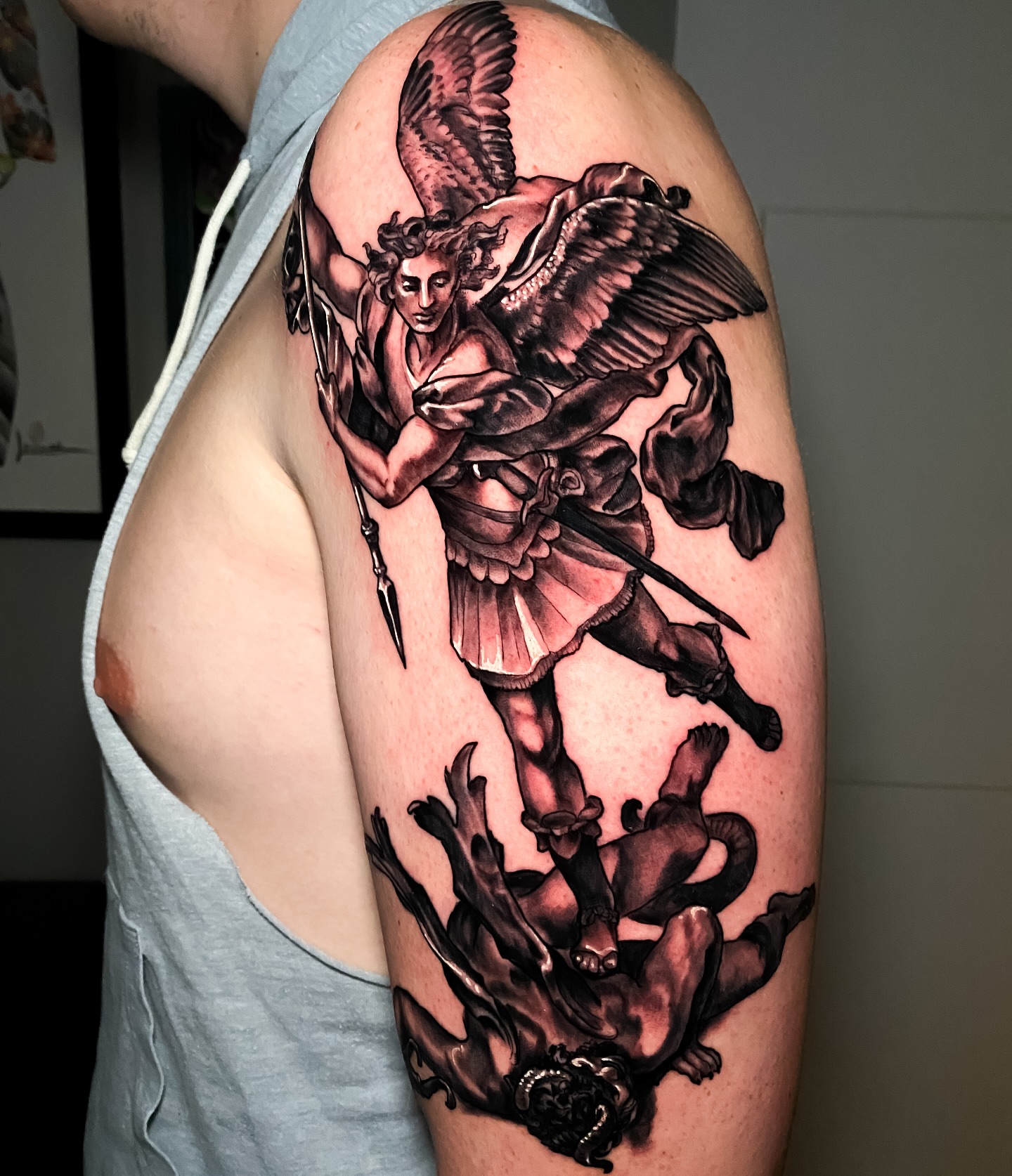 Angel slaying demon realism tattoo on the upper arm by Eric James, Phoenix, Arizona