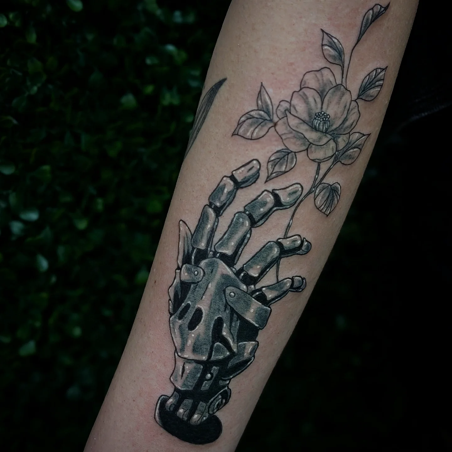 Robotic hand with flower realism tattoo on the forearm by Marlayna Connelly