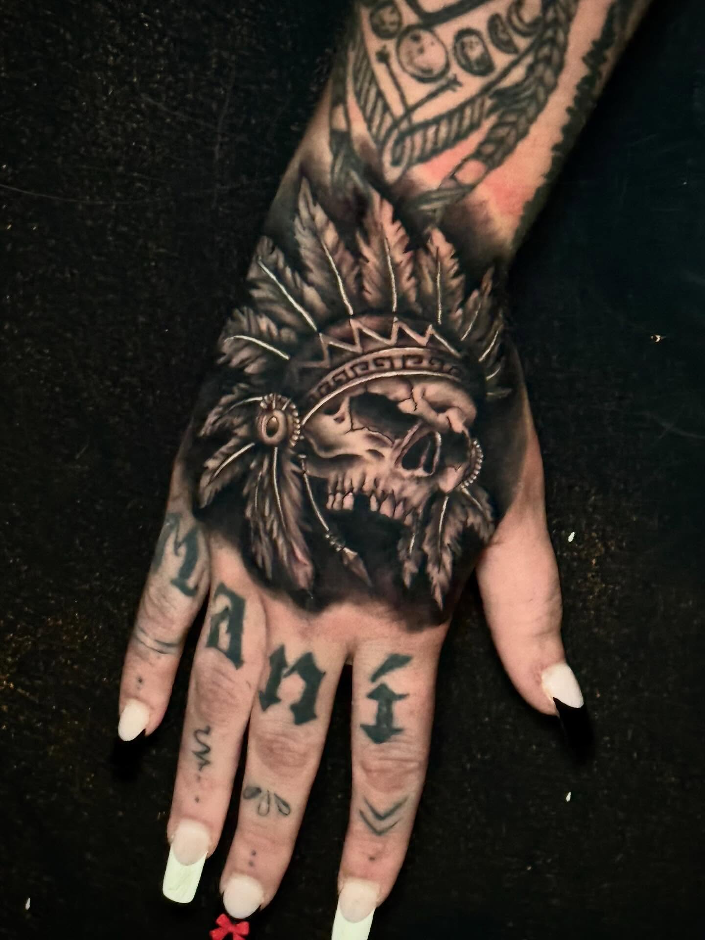 Skull with headdress realism tattoo on the hand by Jeremy Carson