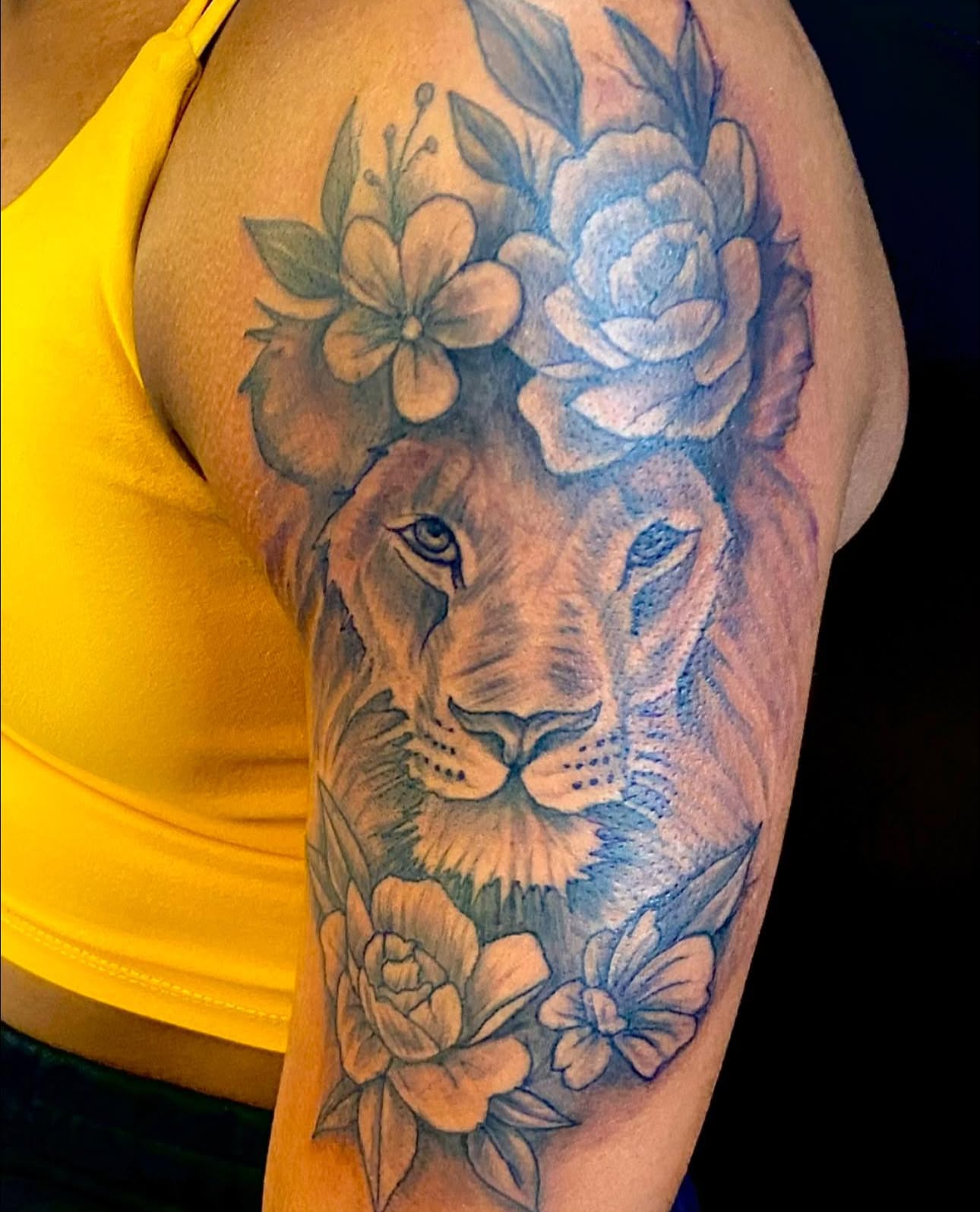 Lion with flowers realism tattoo on the shoulder by Adrian Shan Carr