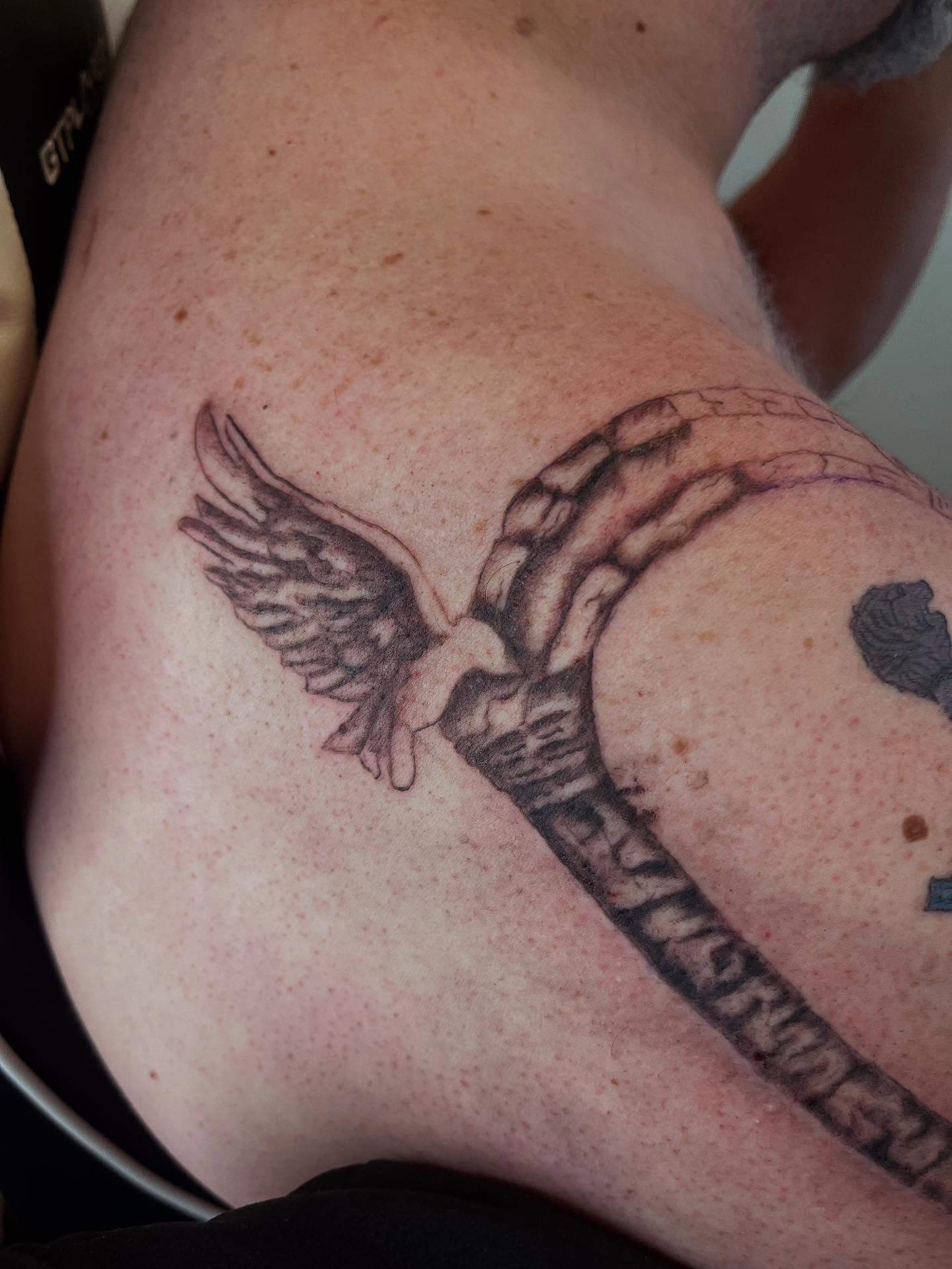 Wings and hands black and grey tattoo on the back by Val Maughan