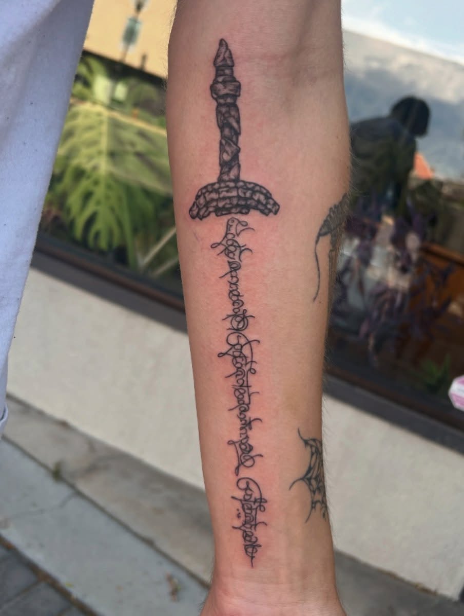 Sword and runes black and grey tattoo on the forearm by Jayda Shell