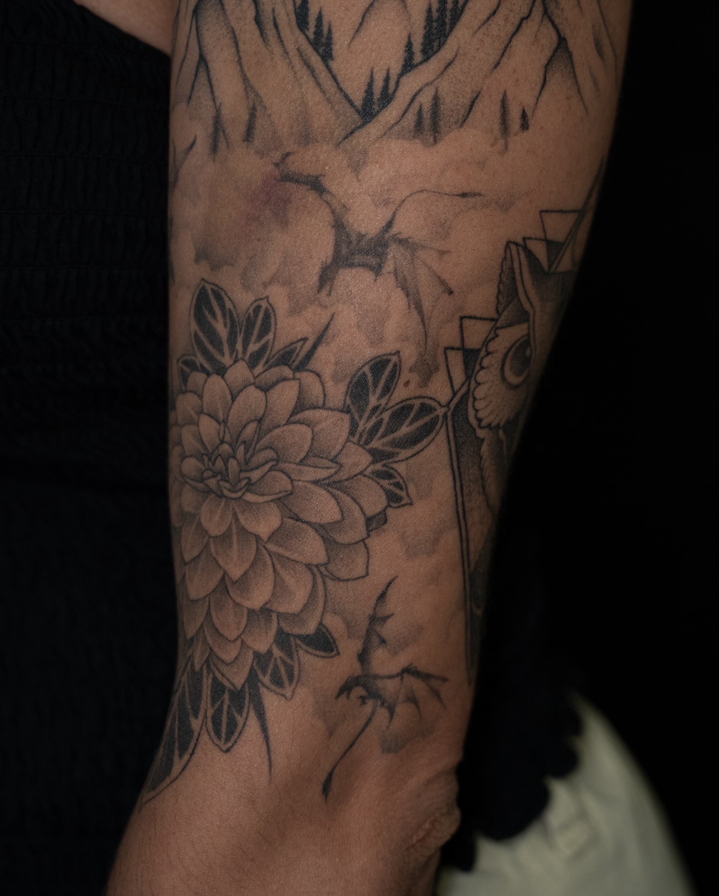 Mountain and flowers realism tattoo on the forearm by Chris Estrada
