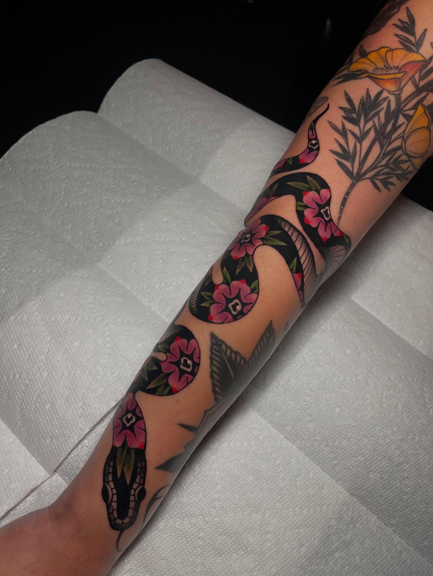 Snake and flowers American traditional tattoo on the forearm by Marqui Watling