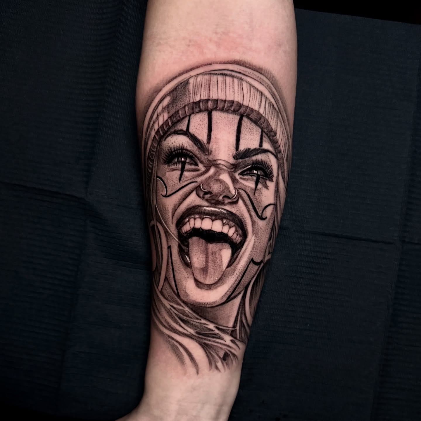 Clown black and grey tattoo on the forearm by Tattoo Artist