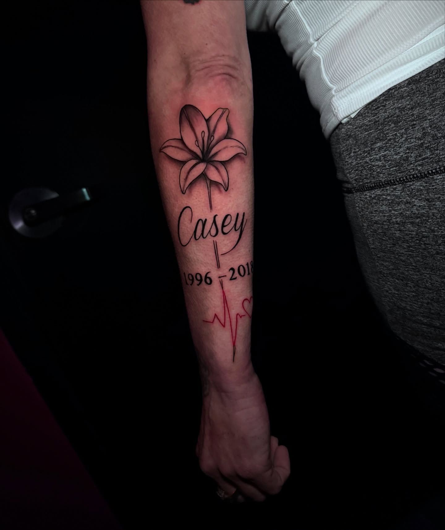Lily and heartbeat black and grey tattoo on the forearm by Ryland - Tattoo Artist