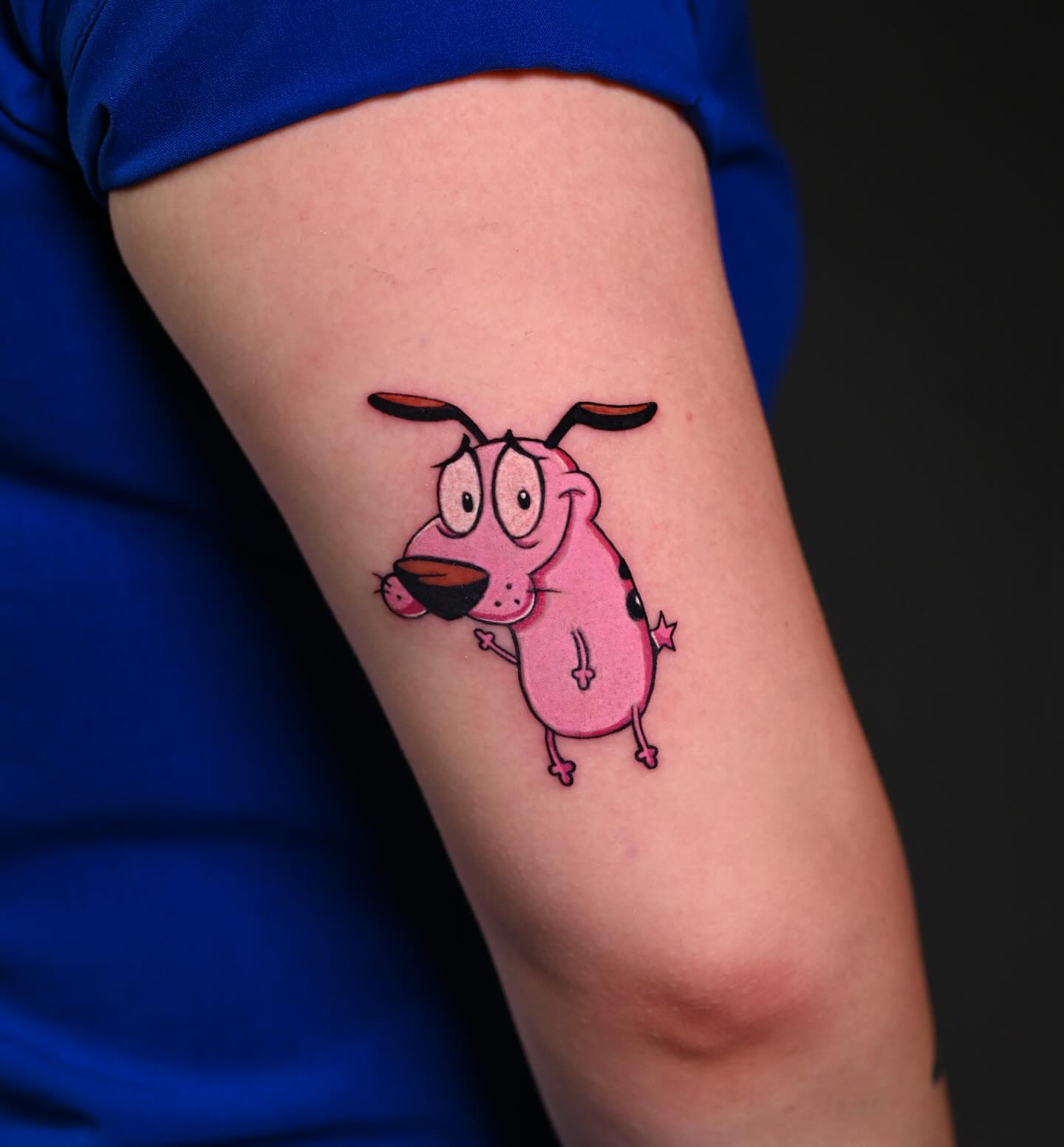 Pink cartoon dog illustrative tattoo on the forearm by Navei
