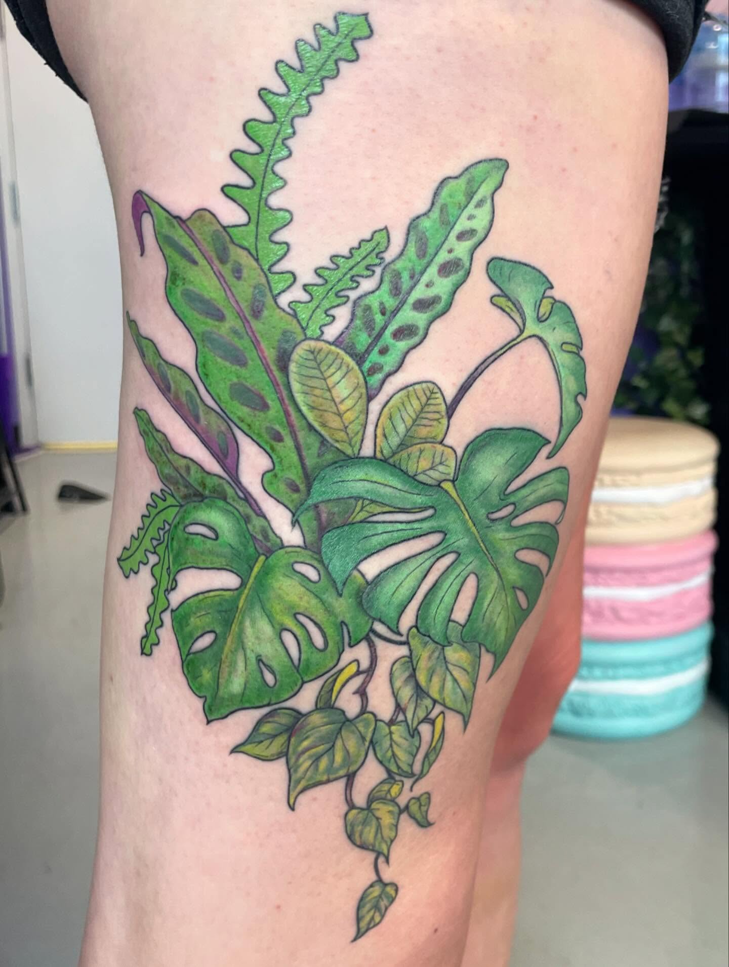Tropical leaves realism tattoo on the thigh by Christin Baumgart