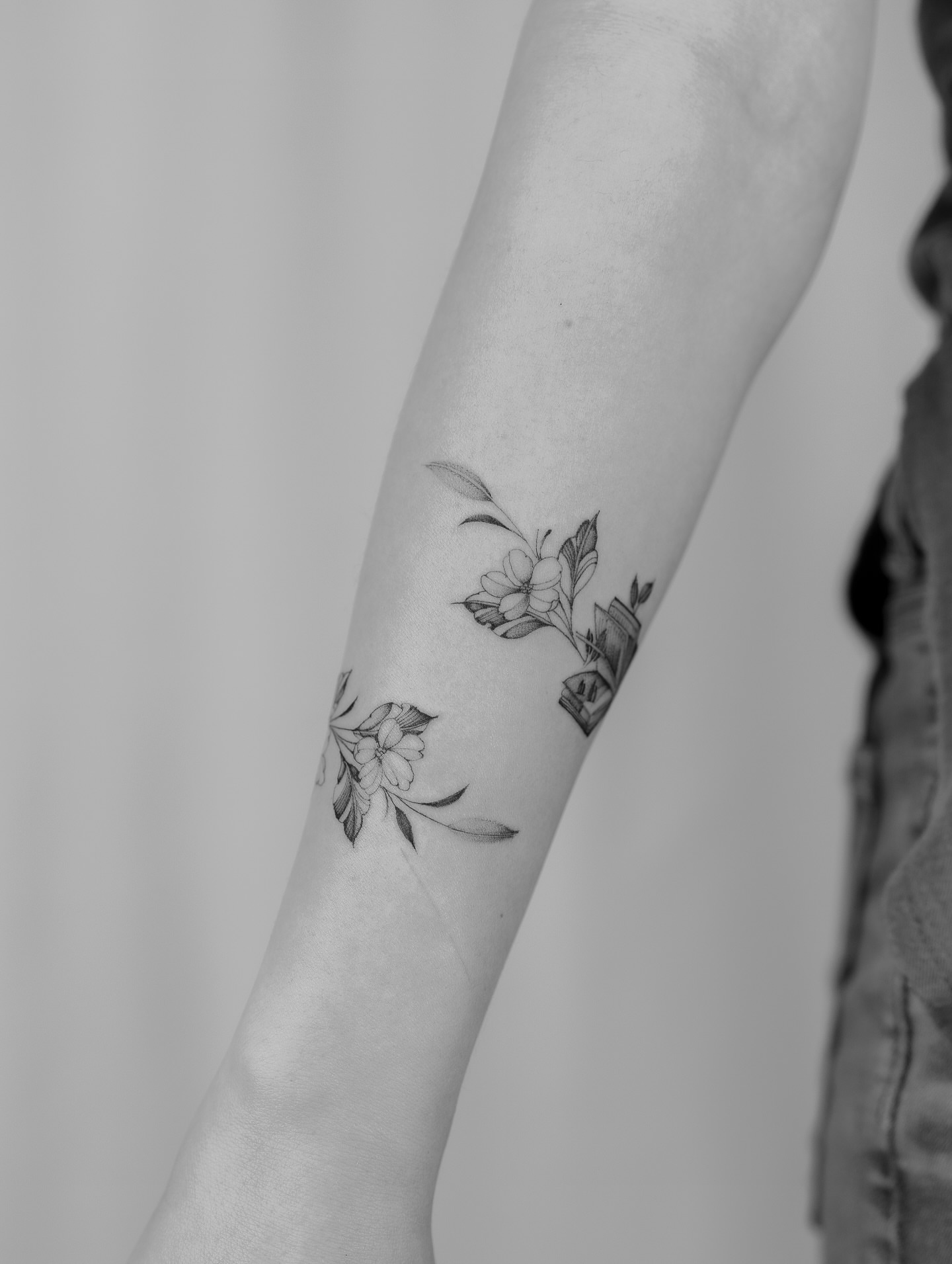 Floral arrangement black and grey tattoo on the forearm by Leo Gao