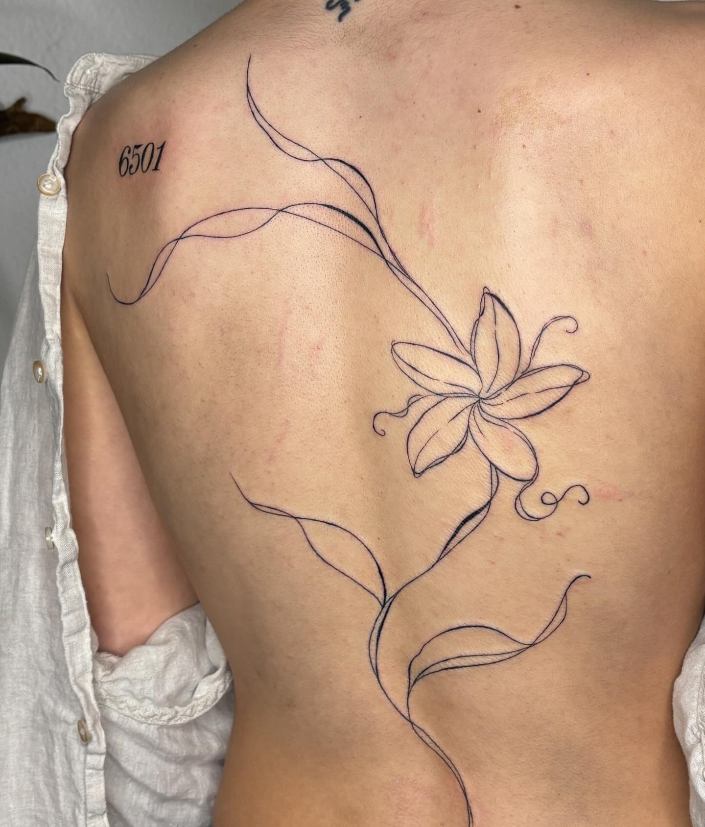 Lily fine line tattoo on the back by alyssa doing tattoos