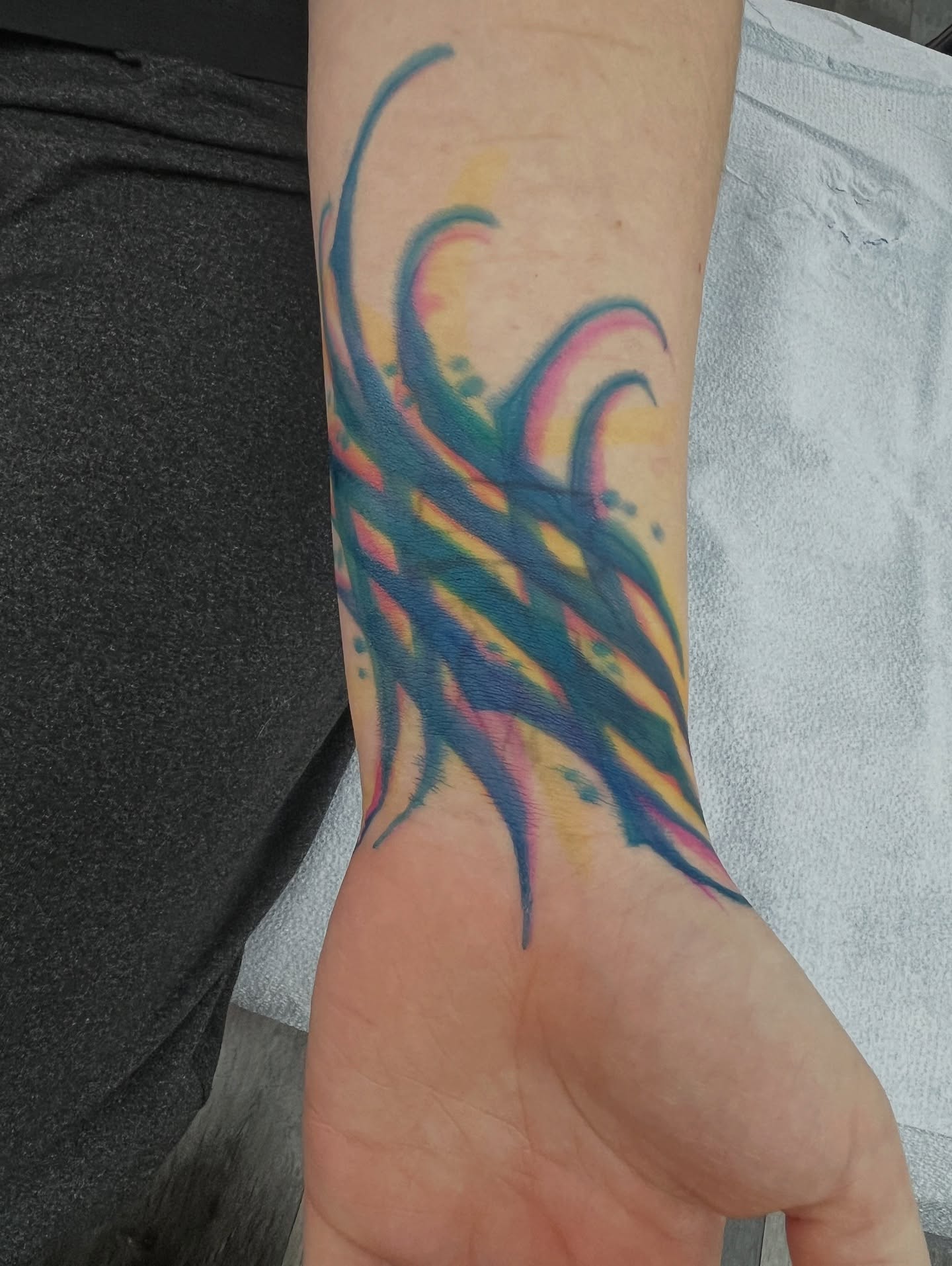 Abstract flame watercolor tattoo on the forearm by BodyArtByAlia