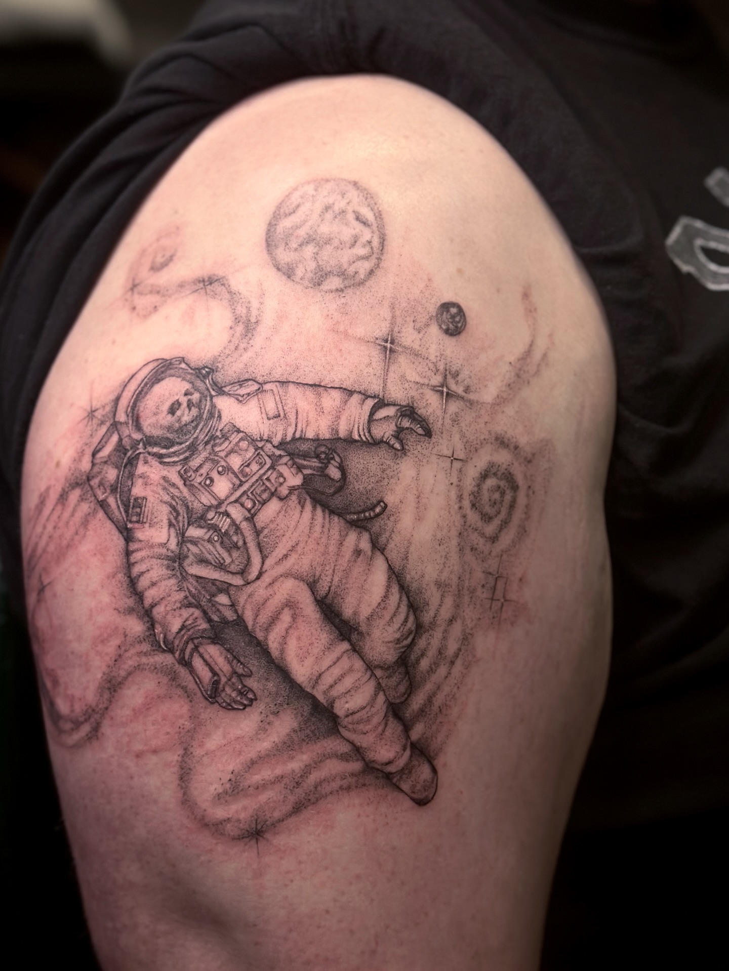 Astronaut floating in space realism tattoo on the shoulder by cora cupid