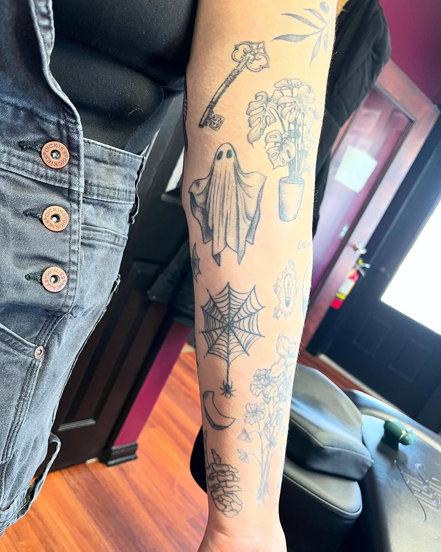 Ghost, spider web, plant, key, flowers black and grey tattoo on the forearm by Kelli Donegan ๐ท