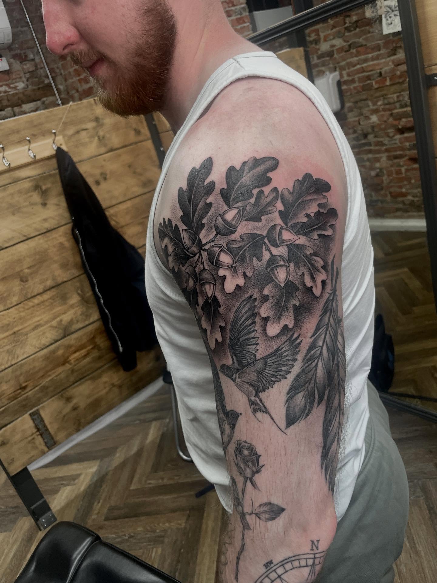 Bird and oak leaves realism tattoo on the upper arm by Grace derby tattooist, Derby